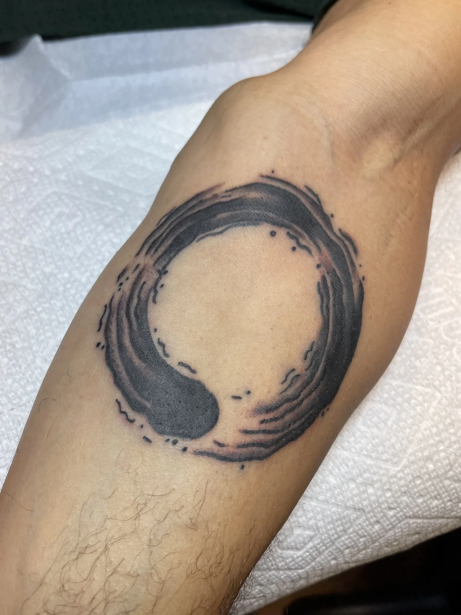 Brushed enso circle blackwork tattoo on an arm.jpg