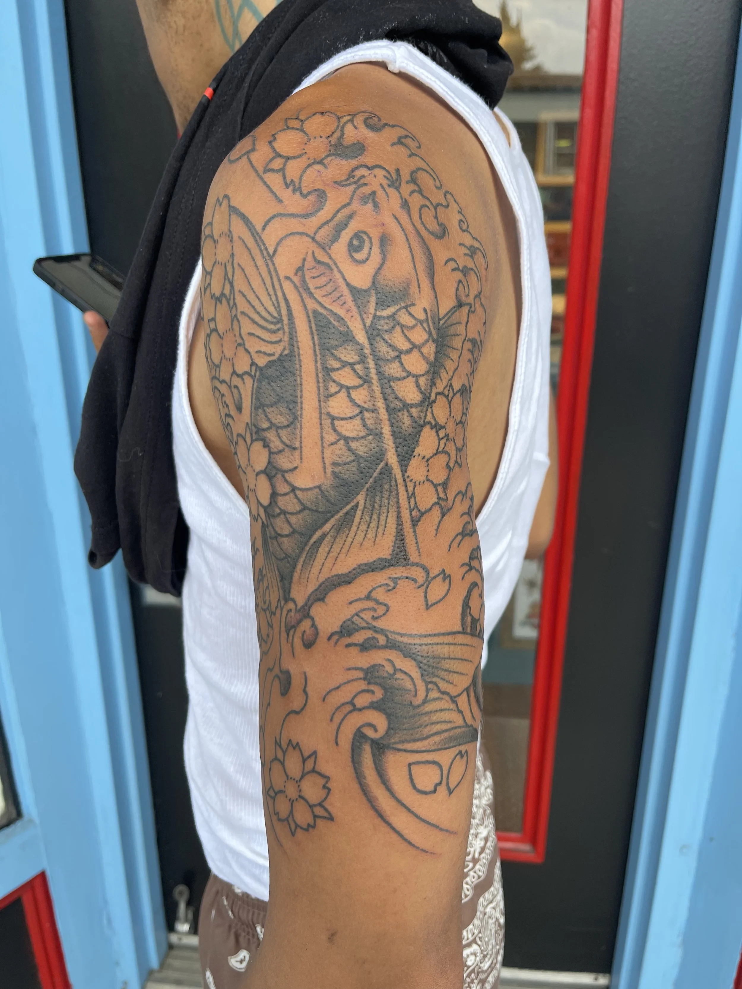 Japanese koi fish half sleeve tattoo with waves and flowers by Electric Lotus Tattoo in NYC