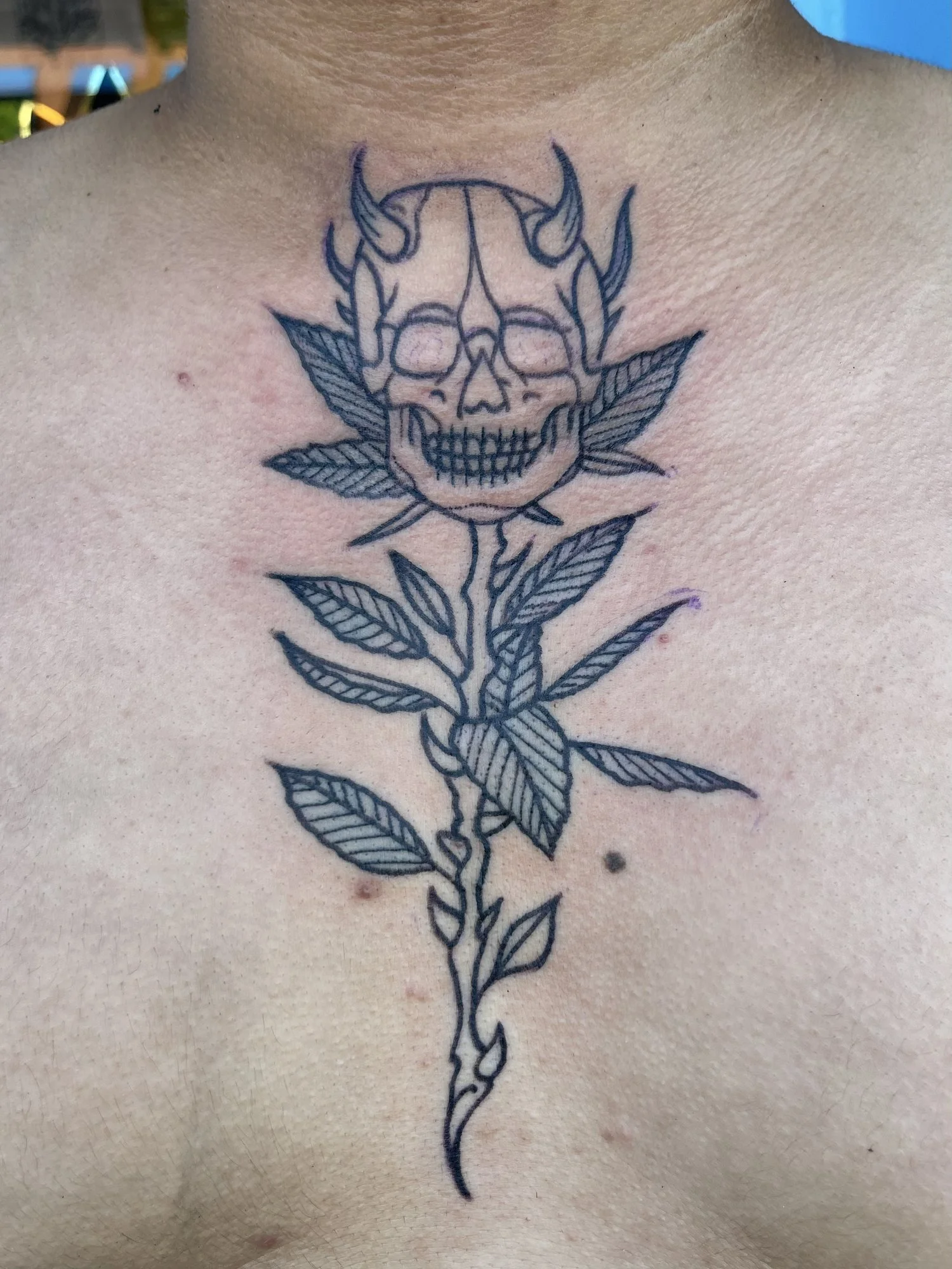 Fine line skull and rose tattoo on a chest.jpg