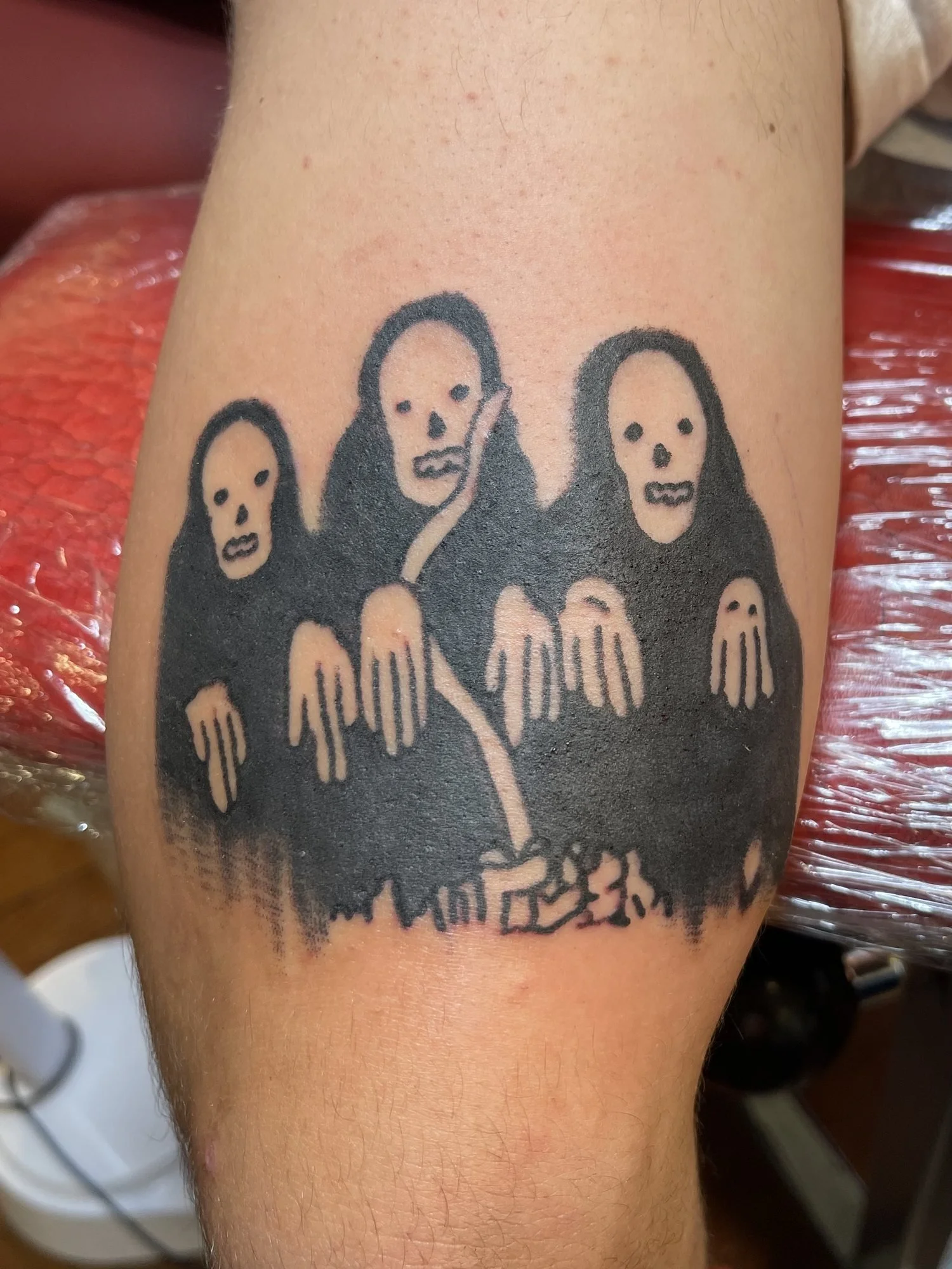 Blackwork tattoo of three hooded figures on a thigh.jpg