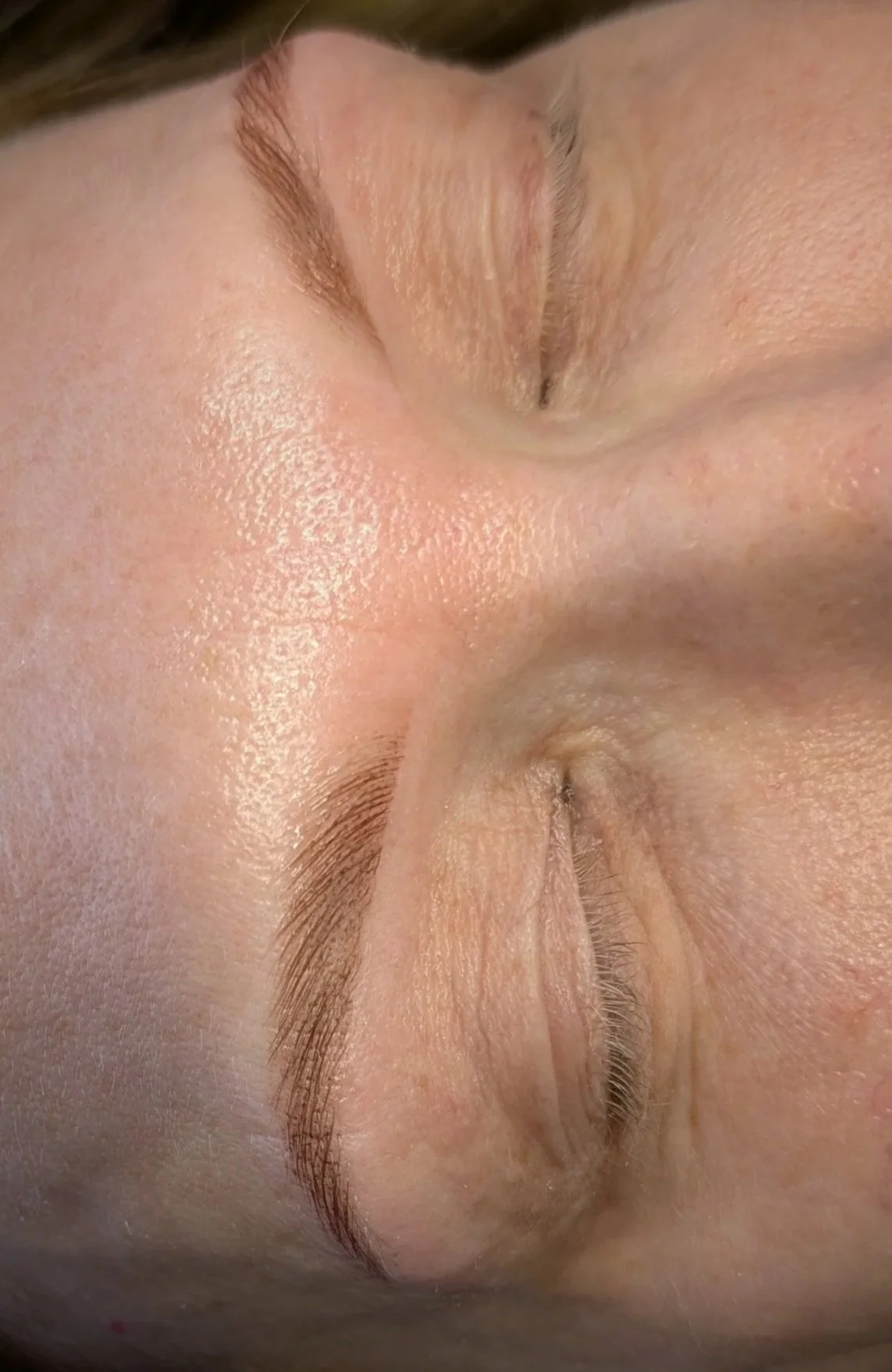 Close-up photo of a person's face with eyes closed, showcasing natural skin texture and eyebrows.