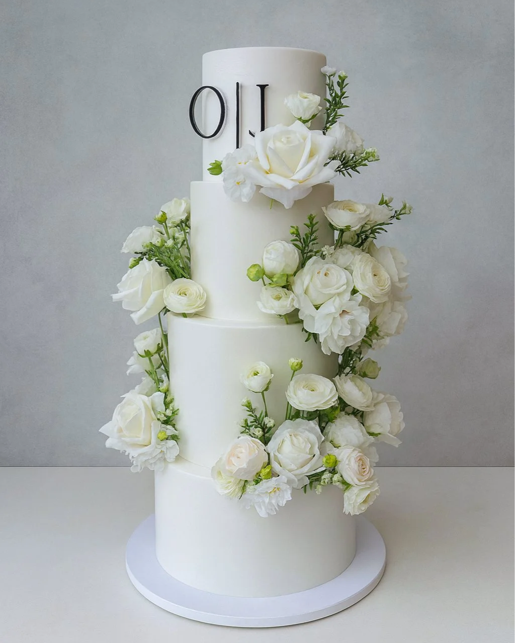 Custom Wedding Cake with couple's initials at the top. Adorned with white Roses.