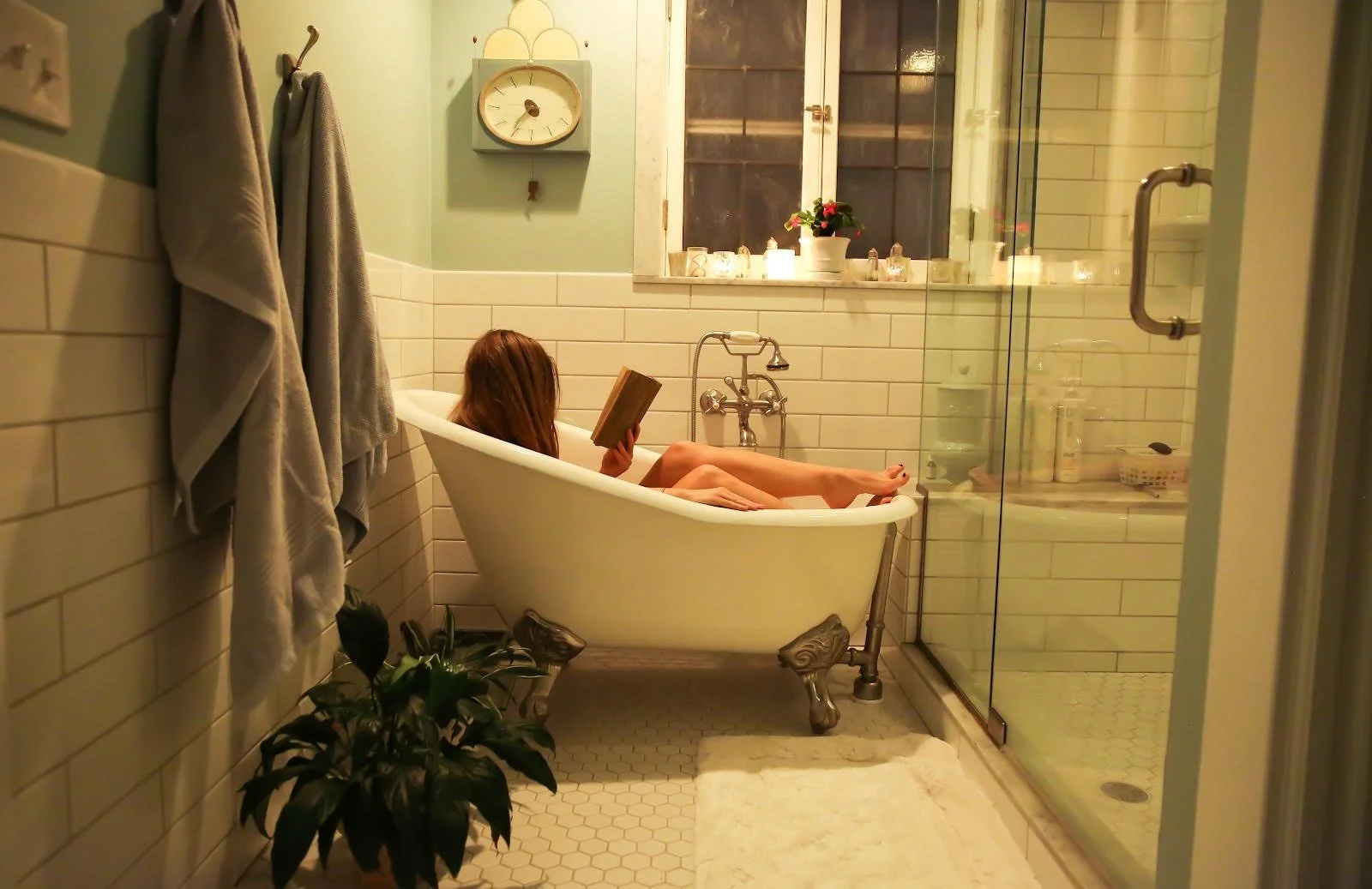 woman relaxing in bathtub reading a book for self-care