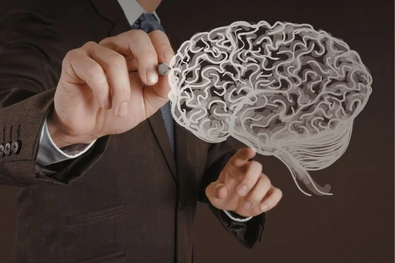Mano de hombre dibujando un cerebro iluminado y conectado como resultado de la aplicación de las neurociencias al coaching