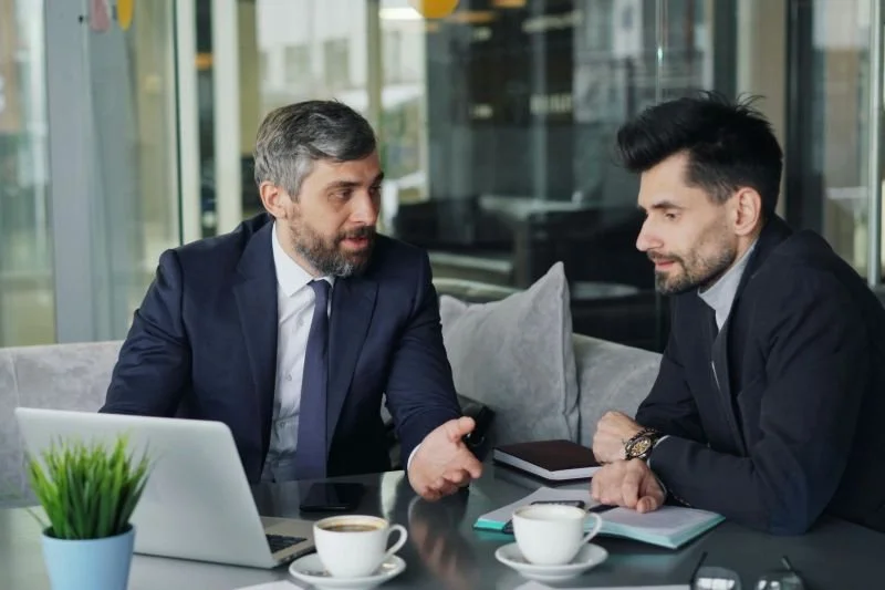 Coach ejecutivo asesorando a directivo de empresa en una charla de café
