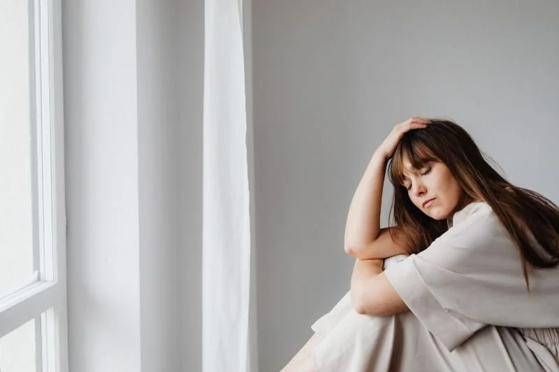 Mujer joven tomándose la cabeza con con gesto de frustración, estrés, indecisión y miedo que necesita coaching