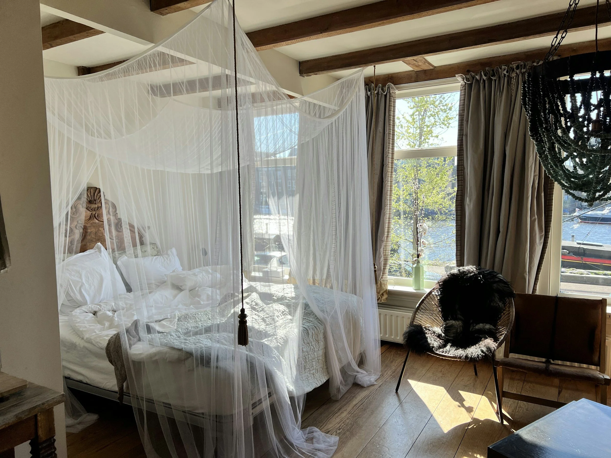 A beautiful bedroom with a canopied bed protecting sleepers from the overhead beams.