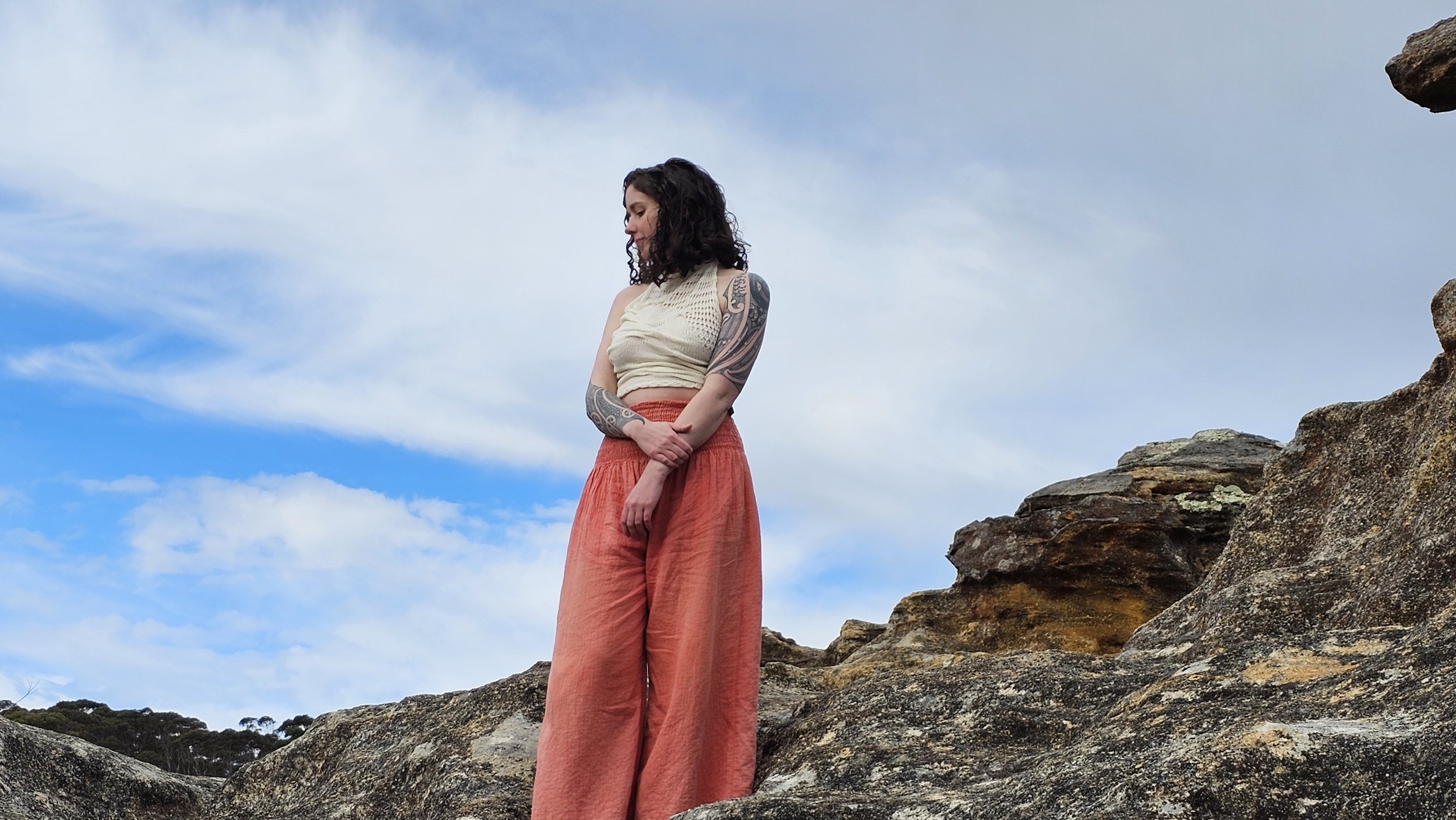 A photo of Lady Woowoo standing on a cliff top, blue sky behind her.