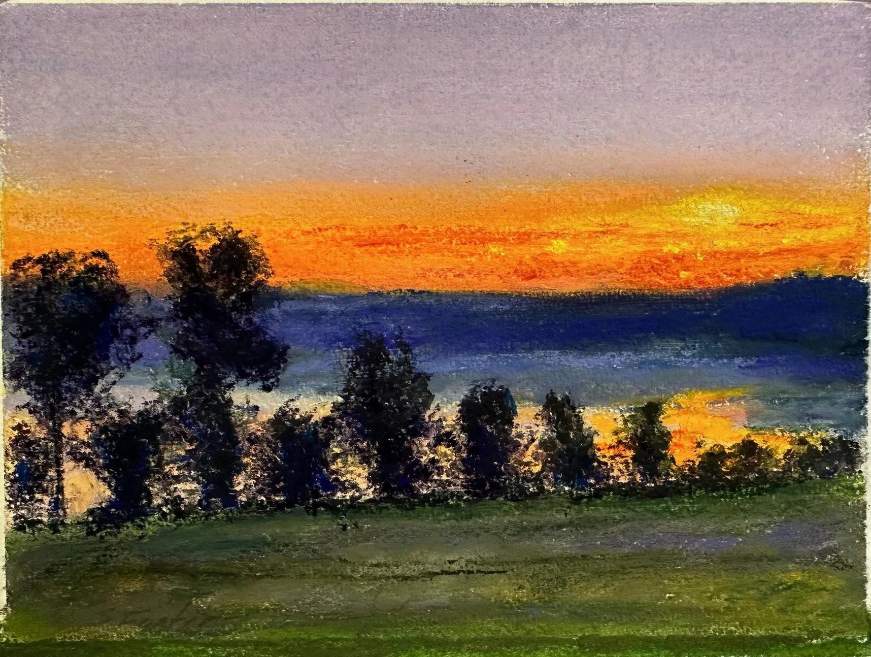 A watercolor painting of a sunset over a landscape. The sky transitions from purple at the top to orange and yellow near the horizon. Silhouettes of trees are in the foreground, with dark green and black shades, and a body of water reflects the sunset colors.
