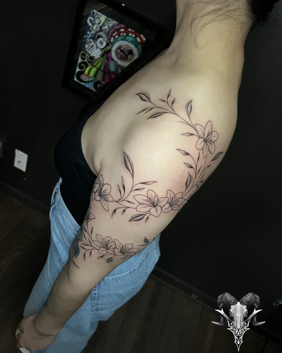Fine line floral vine tattoo flowing around the upper arm by Mi Vida Tattoos