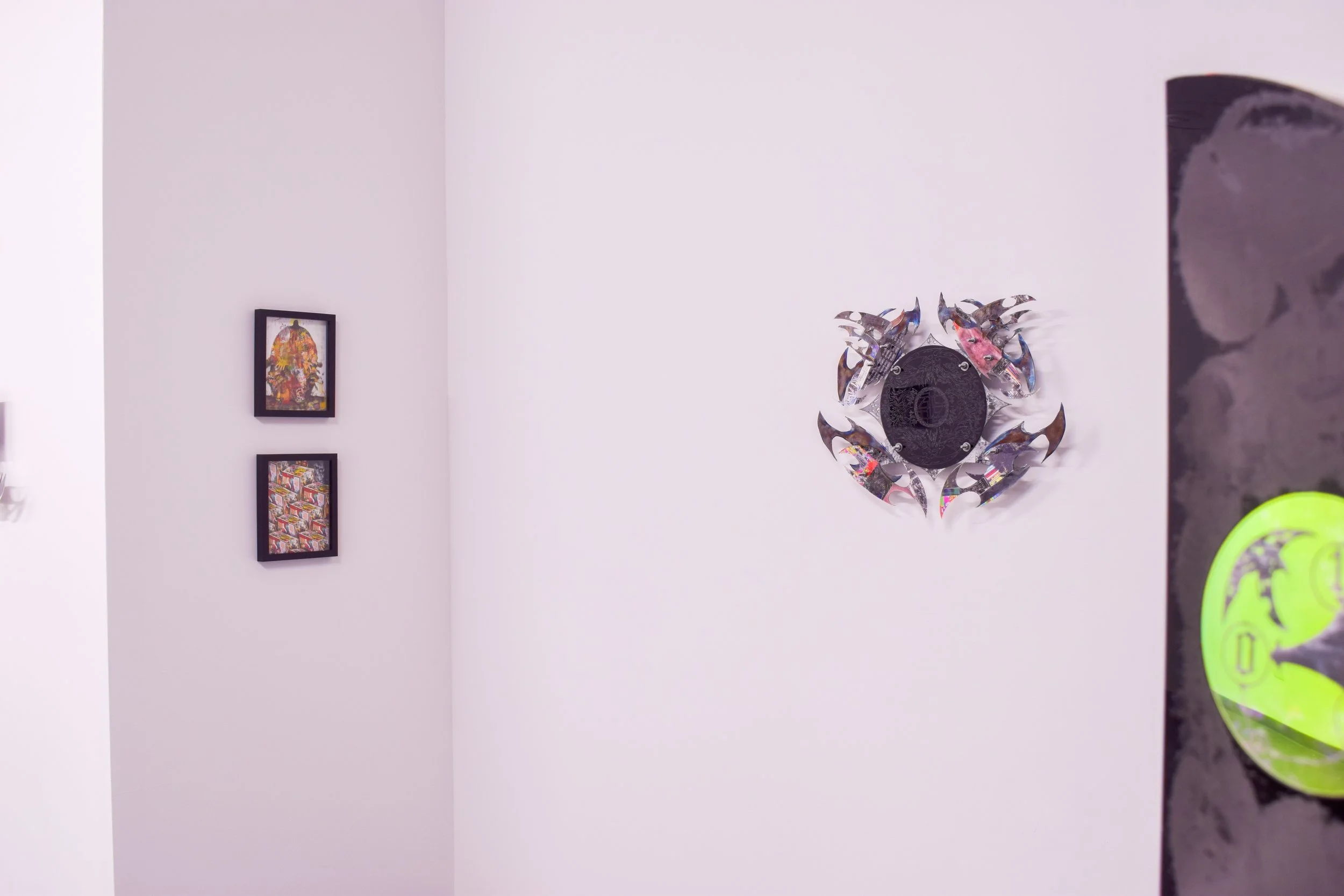 Decorative wall art featuring a circular arrangement of metallic, colorful fish sculptures on a white wall.