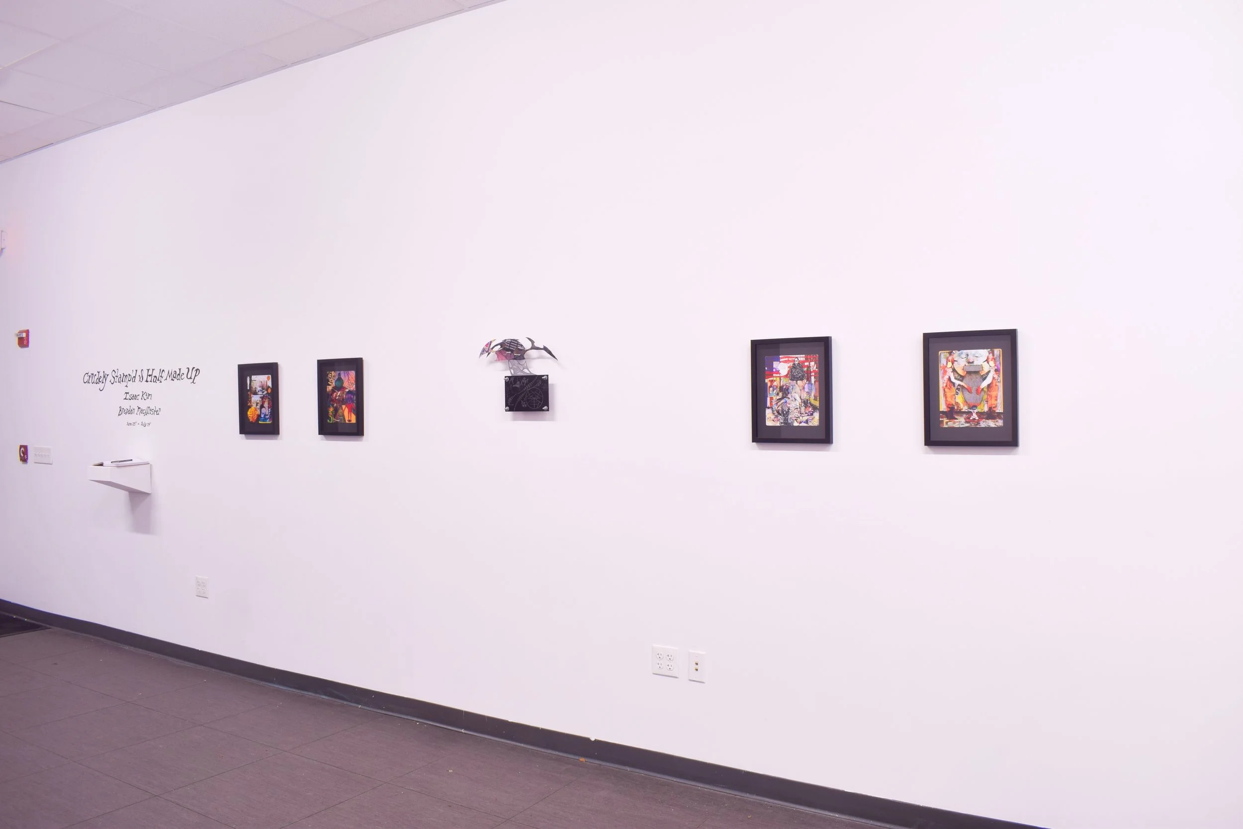Gallery wall displaying five framed abstract artworks and a metal sculpture, with wall text reading 'Crusley Stramped's Heart Made UP' and artist's name Isaac Keen.