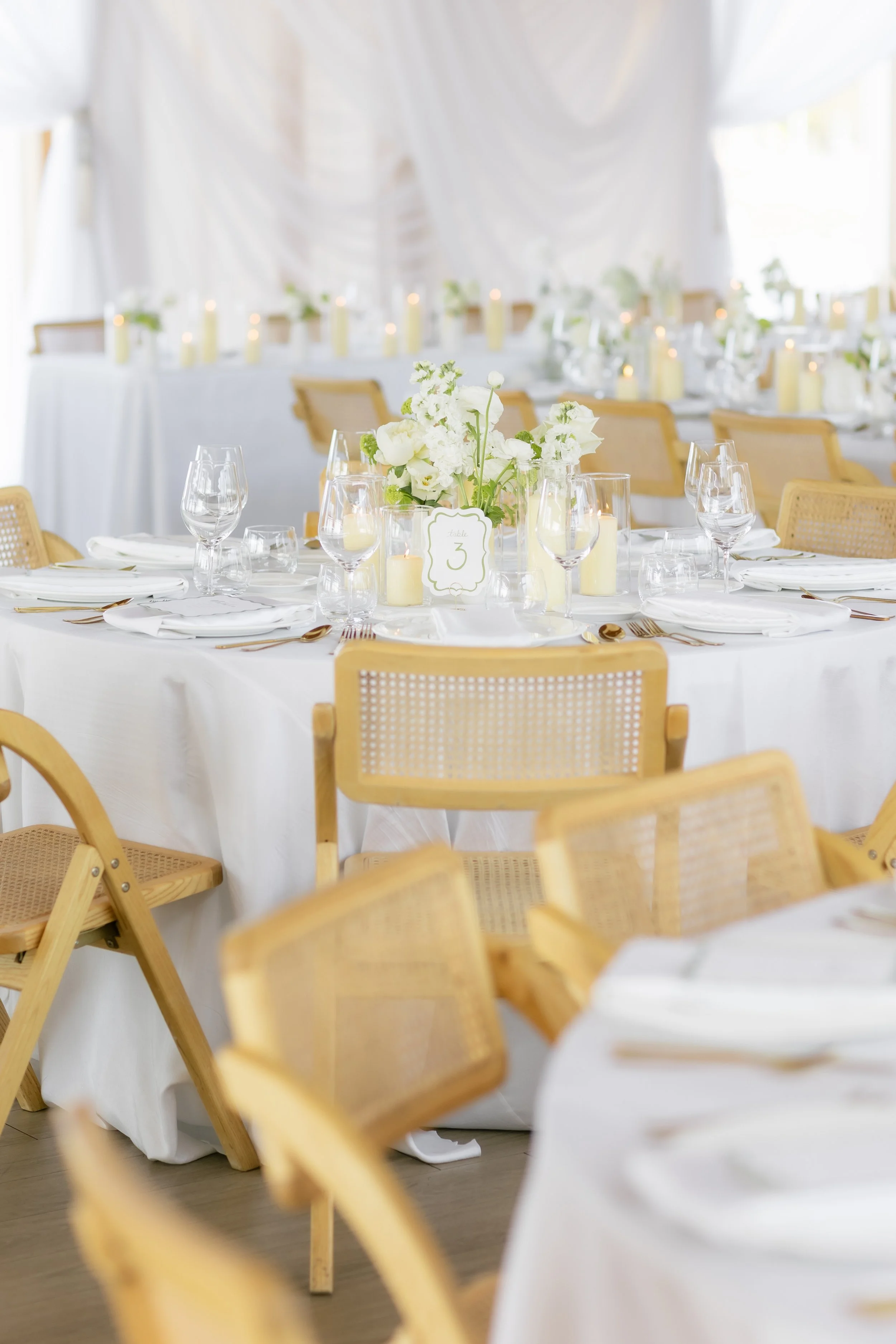 Elegant dinner table setting with salads, candles, and greenery centerpieces in a warmly lit dining space.