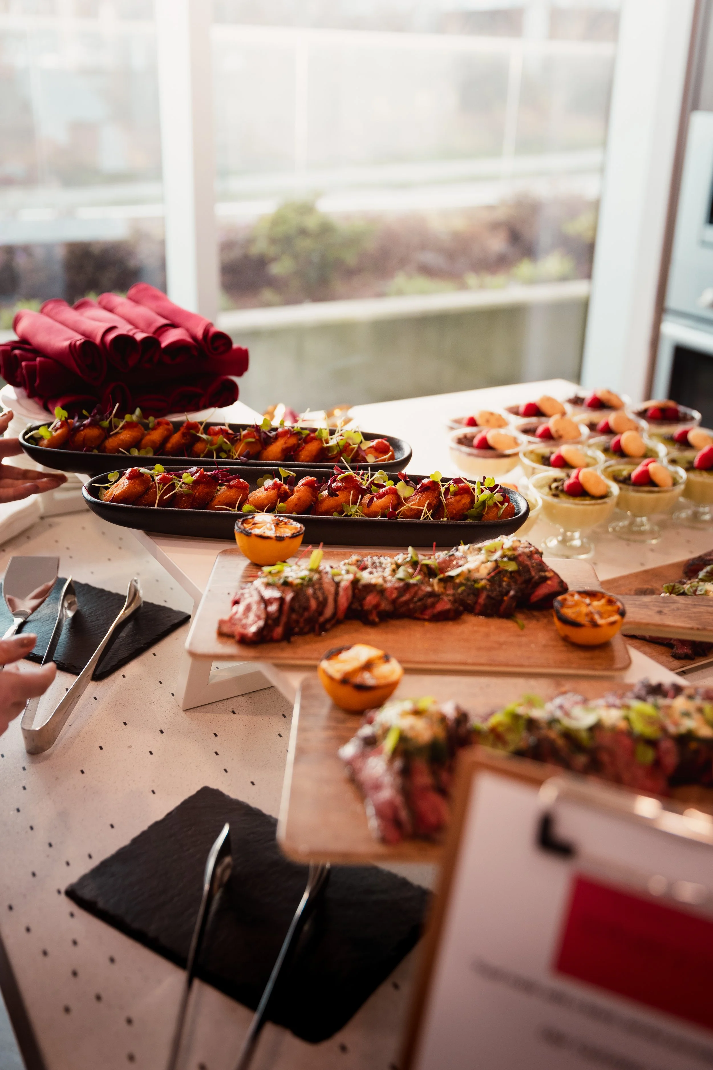 Buffet table with charcuterie, assorted cheeses, and utensils in a restaurant setting.