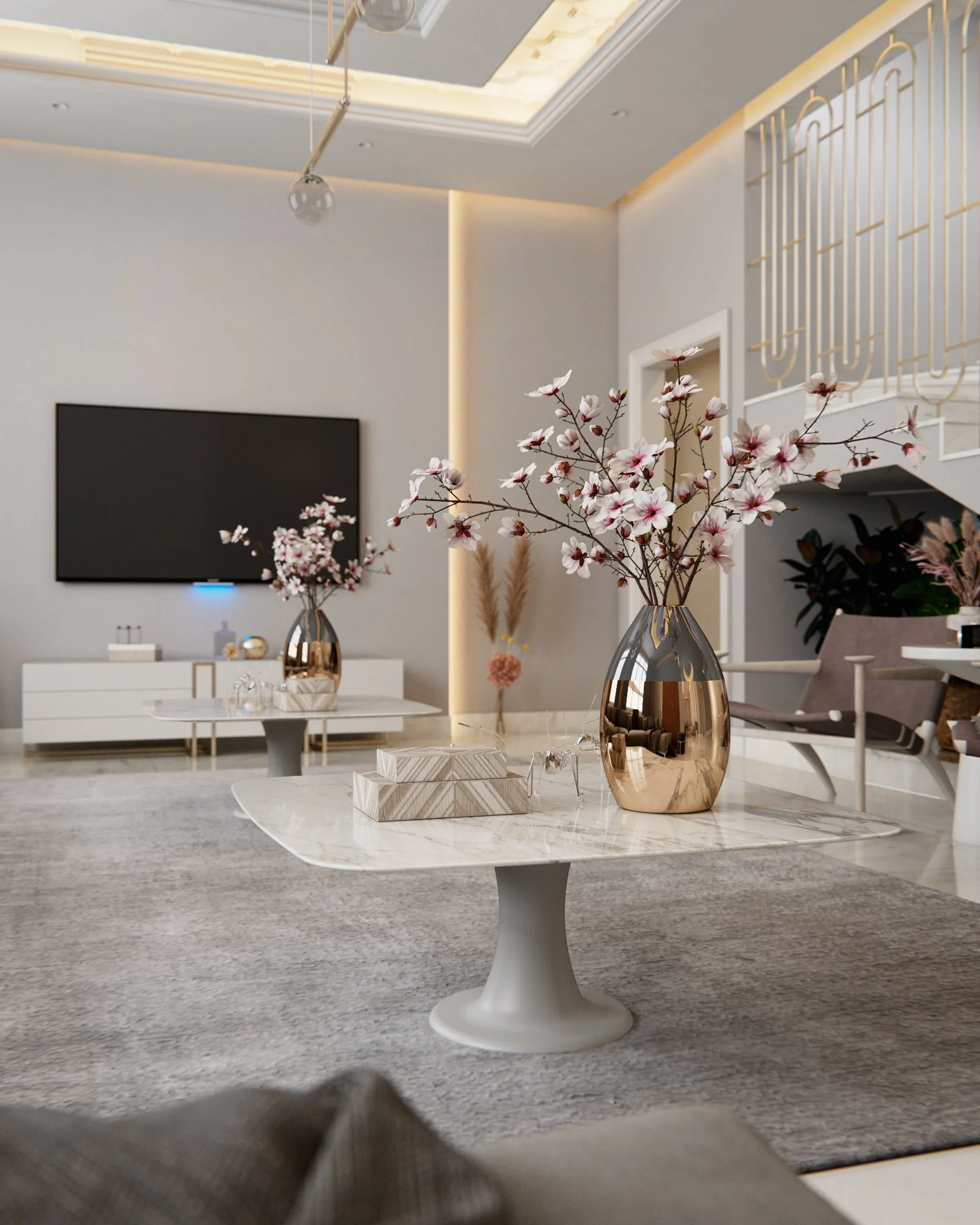 A modern living room with a marble coffee table holding a metallic vase filled with pink and white flowers, a TV mounted on the wall, and a gray rug on the floor.