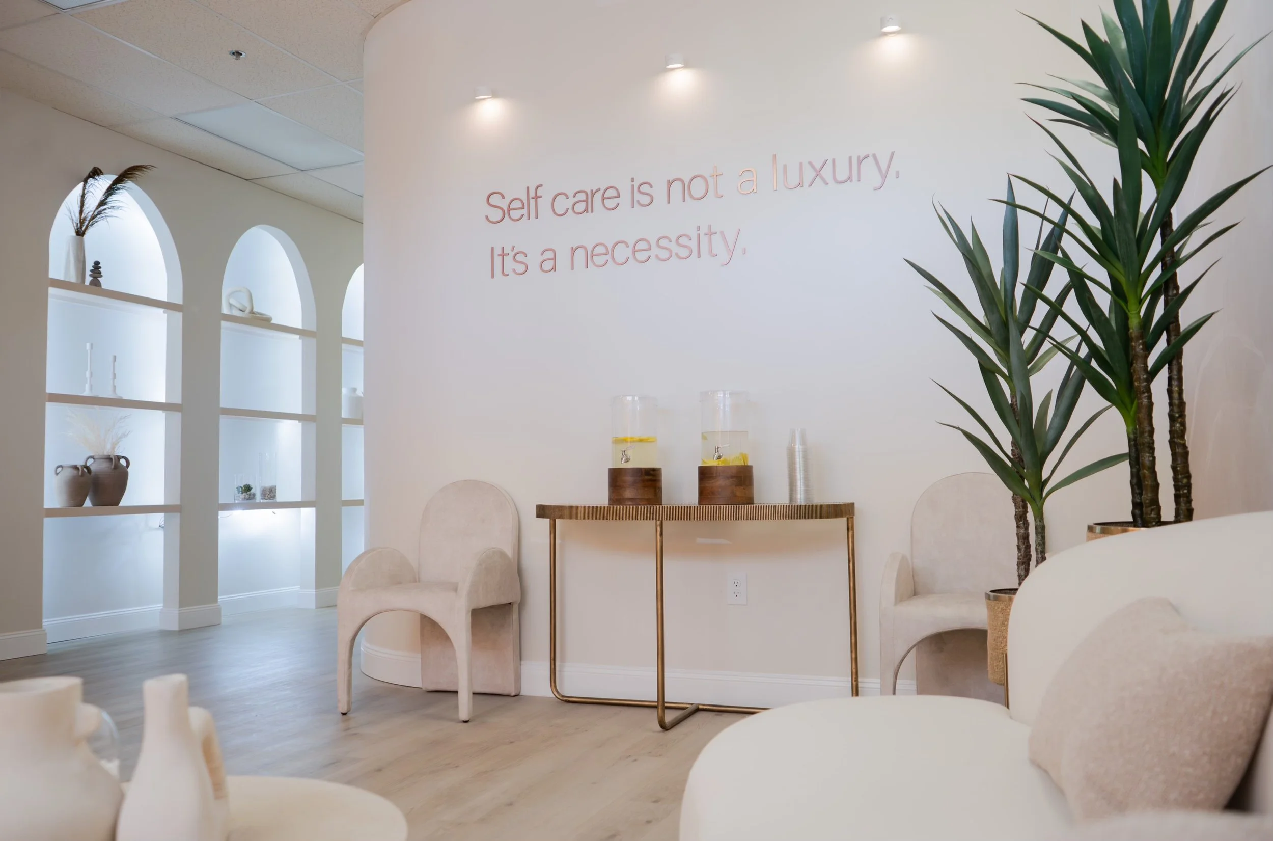 Minimalist spa or wellness center interior with plants, soft chairs, and a motivational quote on the wall.