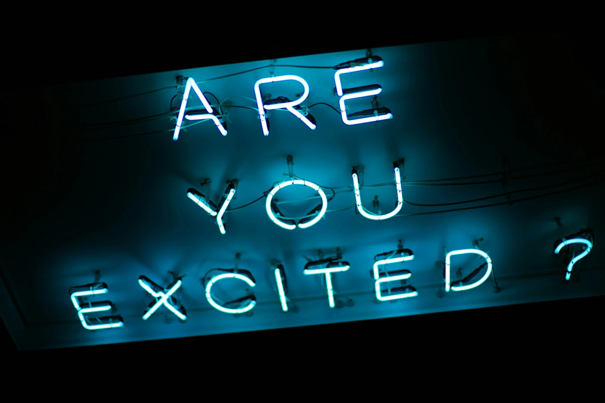 Neon sign with the words "ARE YOU EXISTED" in blue light, partially visible and mounted on a wall.