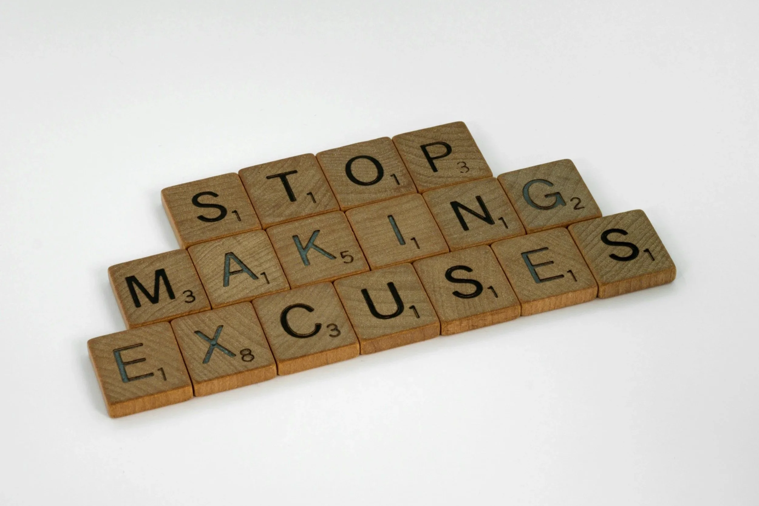 A collection of wooden Scrabble tiles spelling out the words "STOP MAKING ME SICK" on a white background.