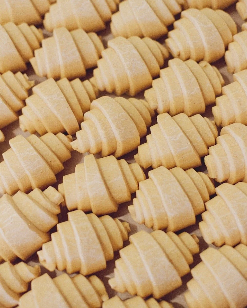 A tray of approximately 20 unbaked croissants neatly packed together in rows.
