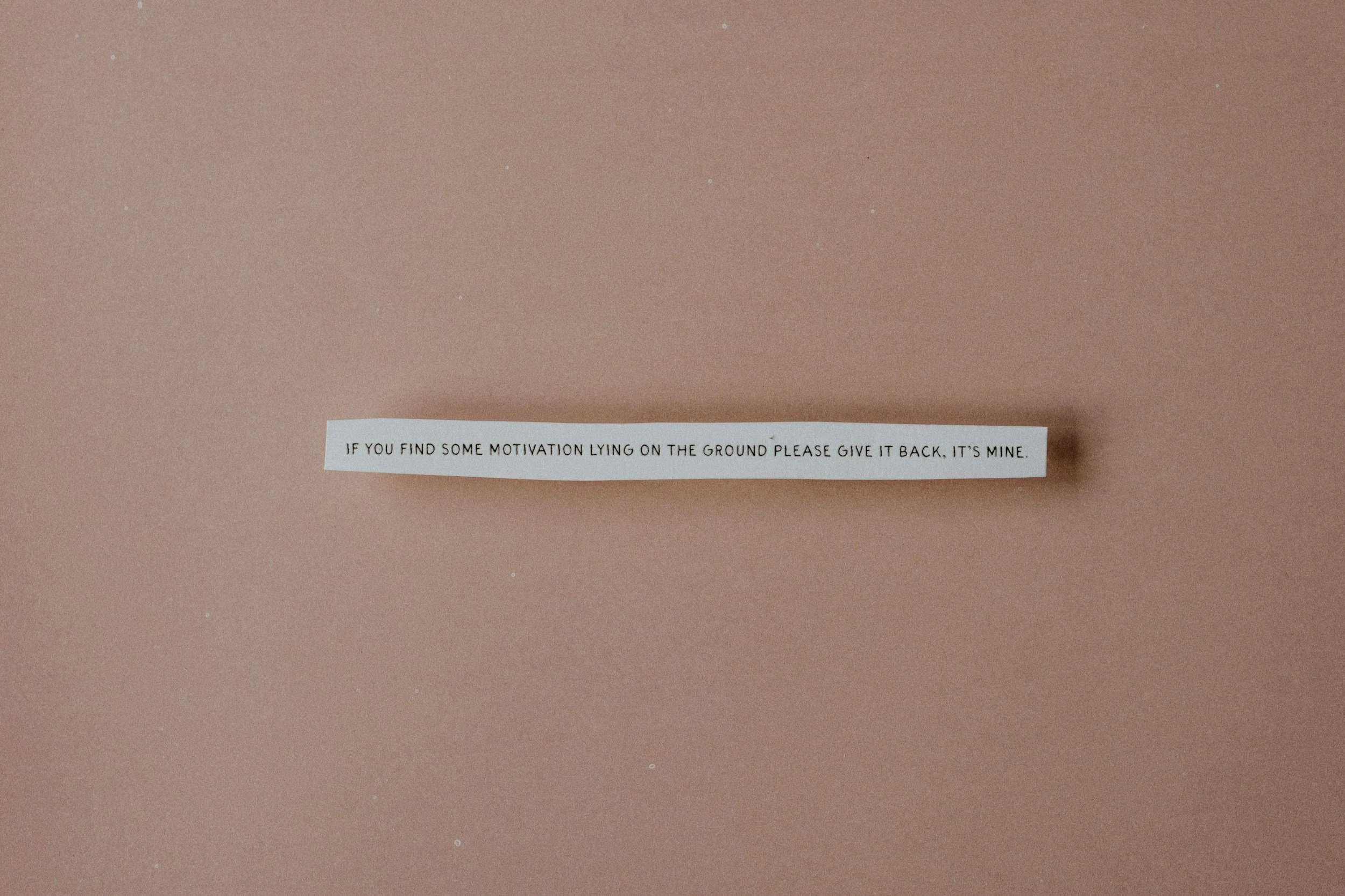 A piece of paper with a motivational message on a pink background.