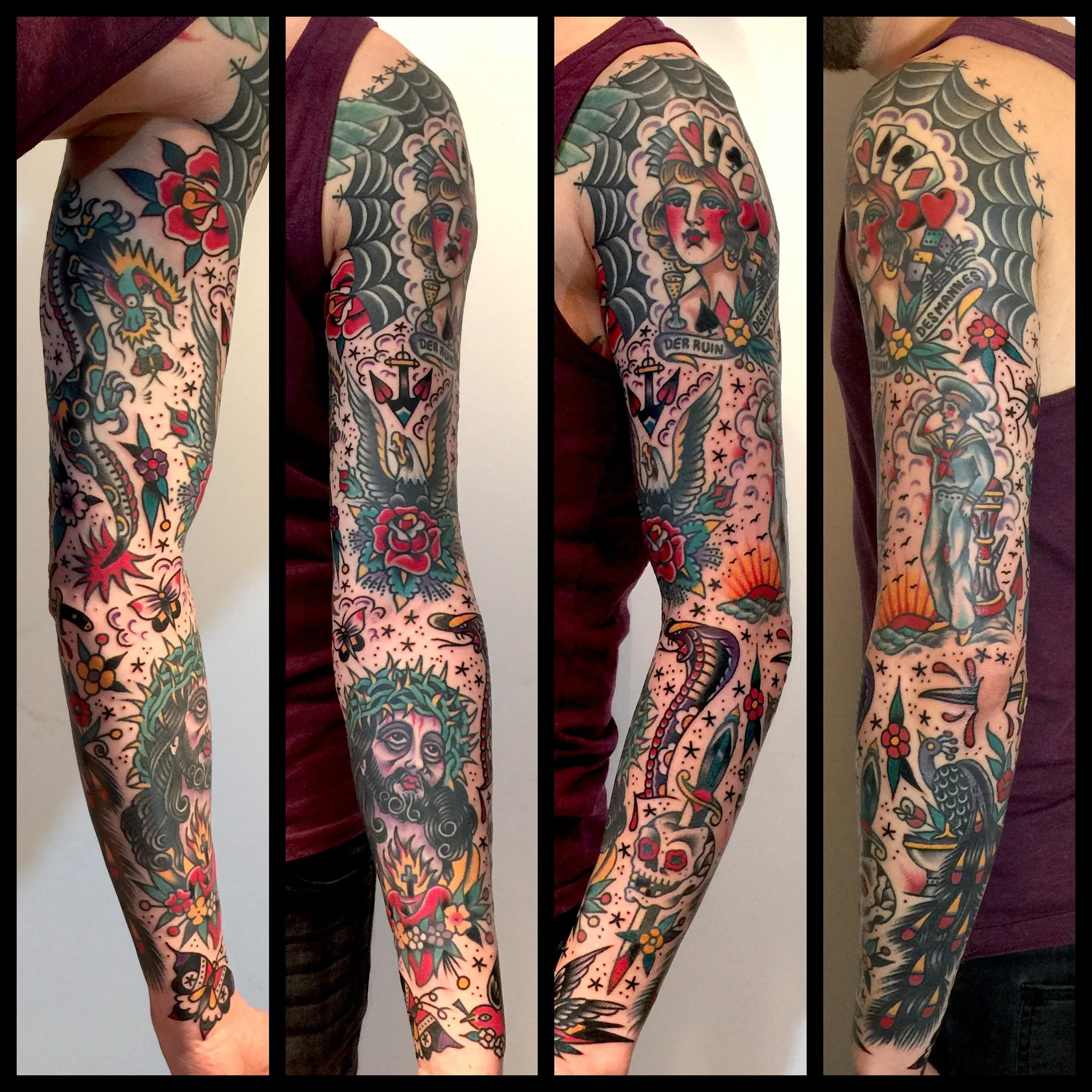 A person's arm with colorful traditional tattoo sleeve including flowers, birds, a woman's portrait with a banner reading "DER RUIN", a snake, a skeleton, and other motifs.