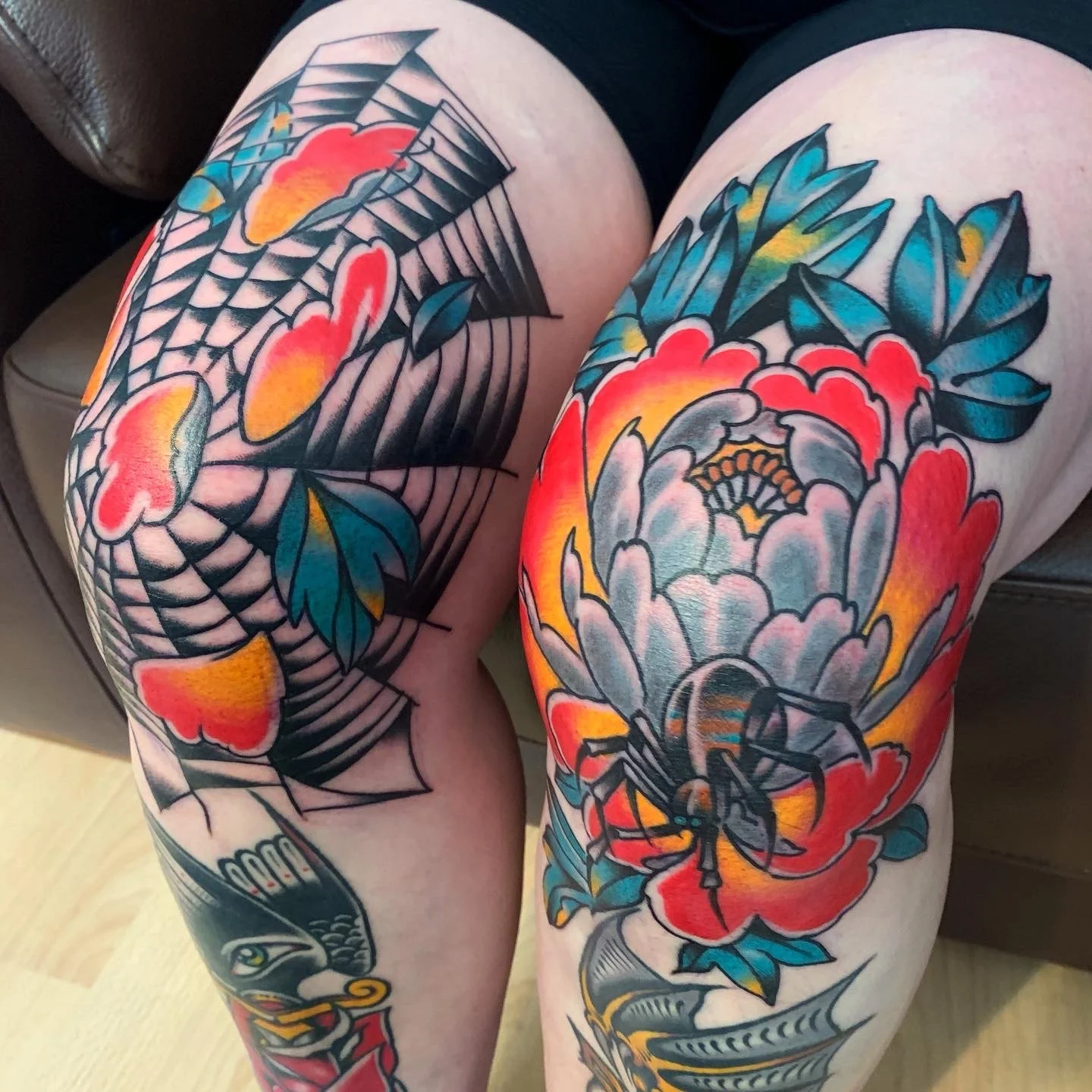 Colorful traditional-style tattoo sleeves on person’s thighs featuring a snake, a spider, a flower, and clouds with vibrant colors like red, blue, yellow, and gray.
