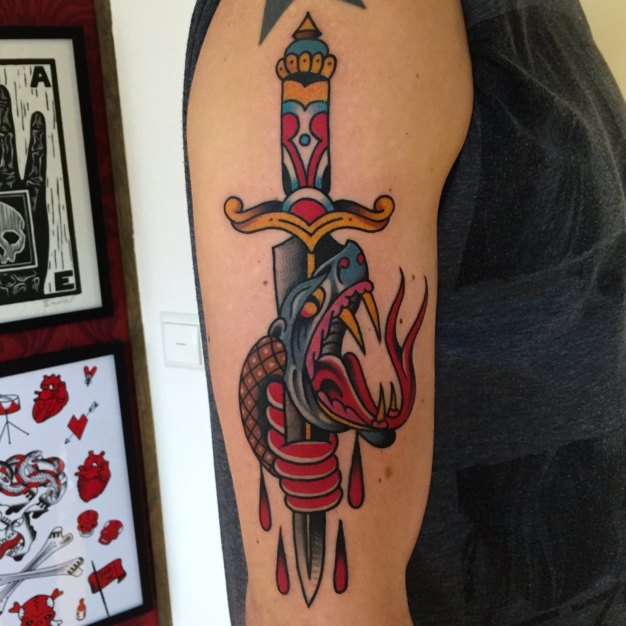 Tattoo of a sword with a snake coiled around it, with a dripping, tongue-like feature at the bottom.