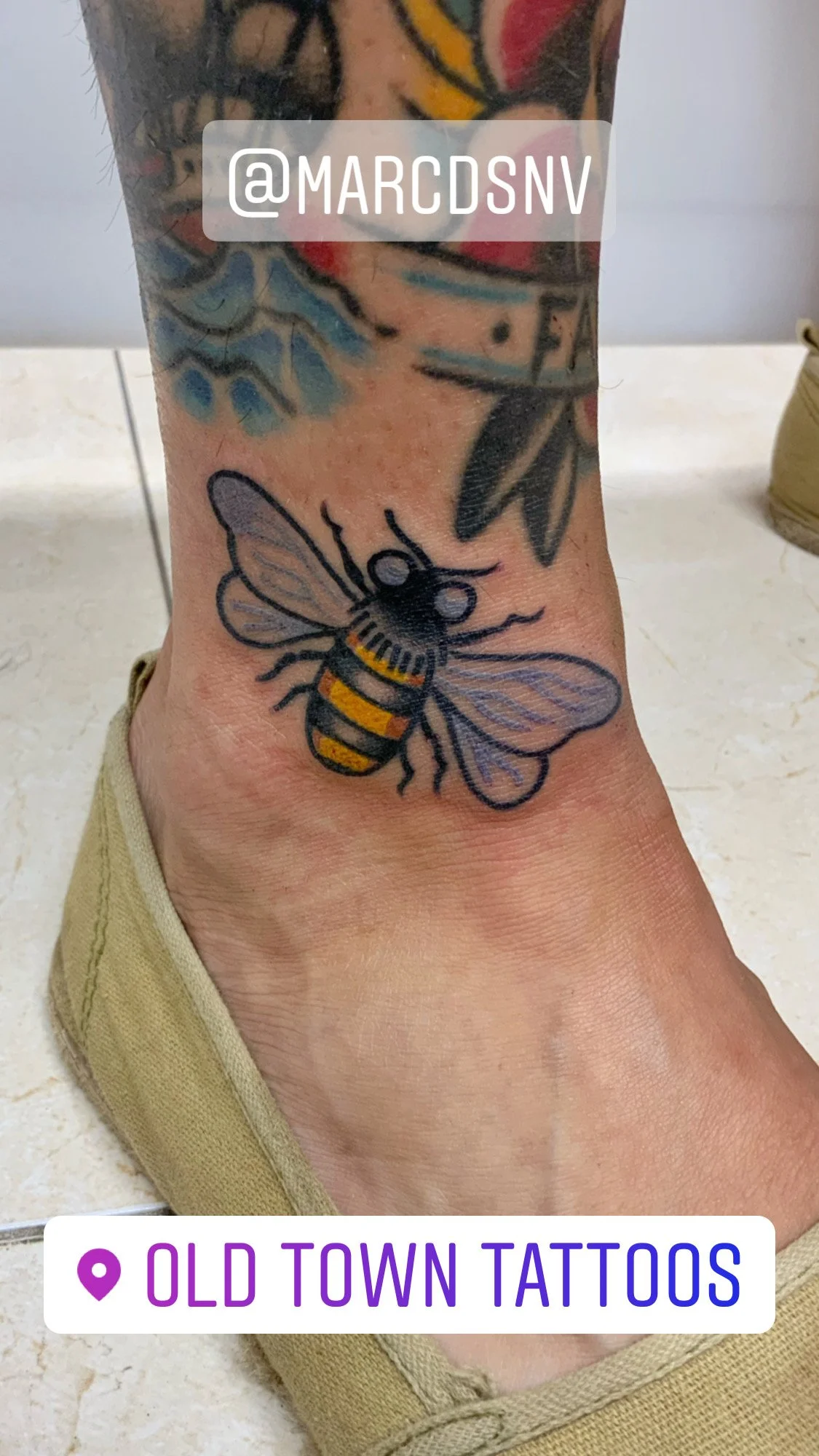 Tattoo of a bee on an ankle.