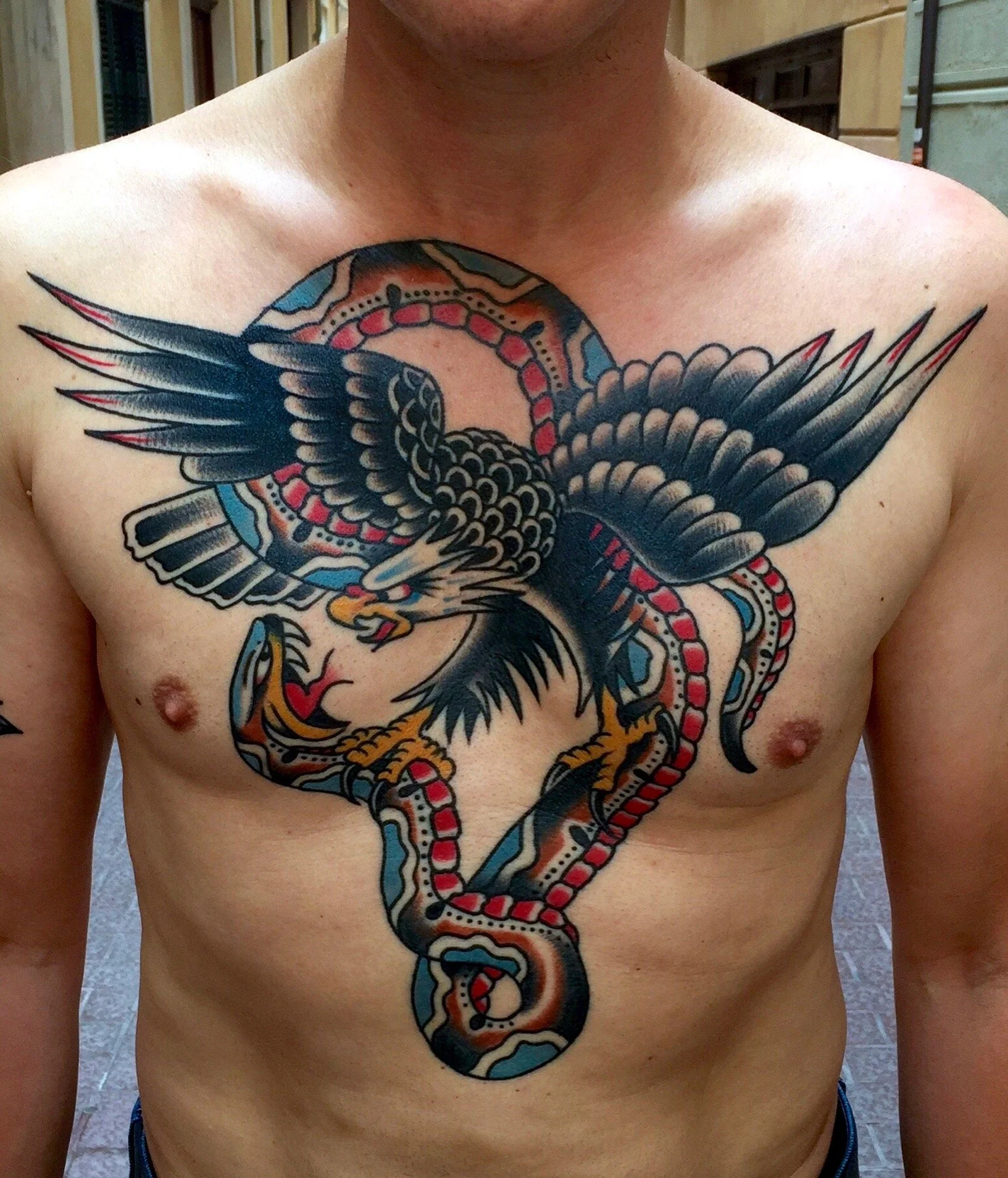 Tattoo of an eagle and a snake in a traditional style on a man's chest.