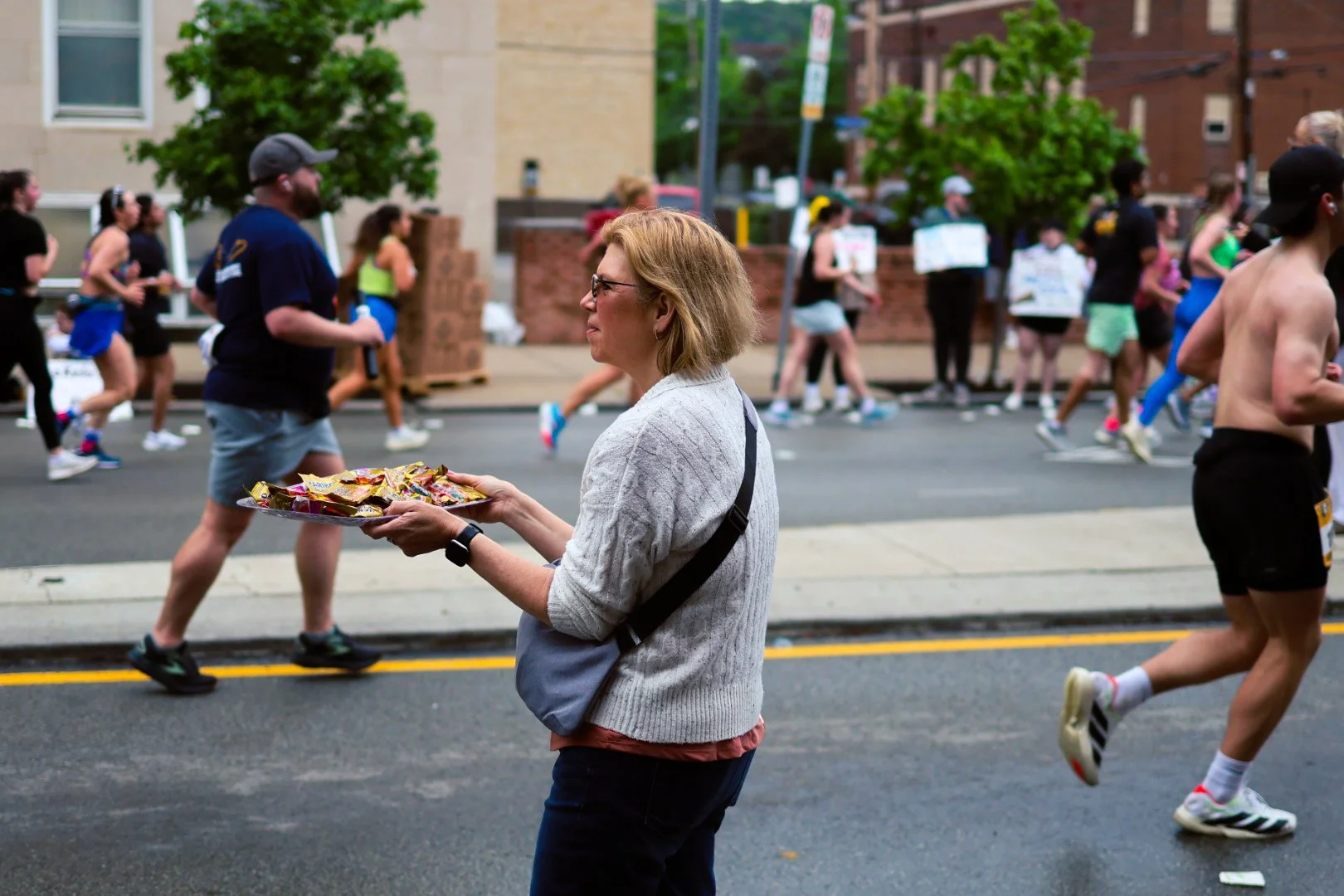 A woman offering snacks to marathon runners during a street race WORK BY DAVEY