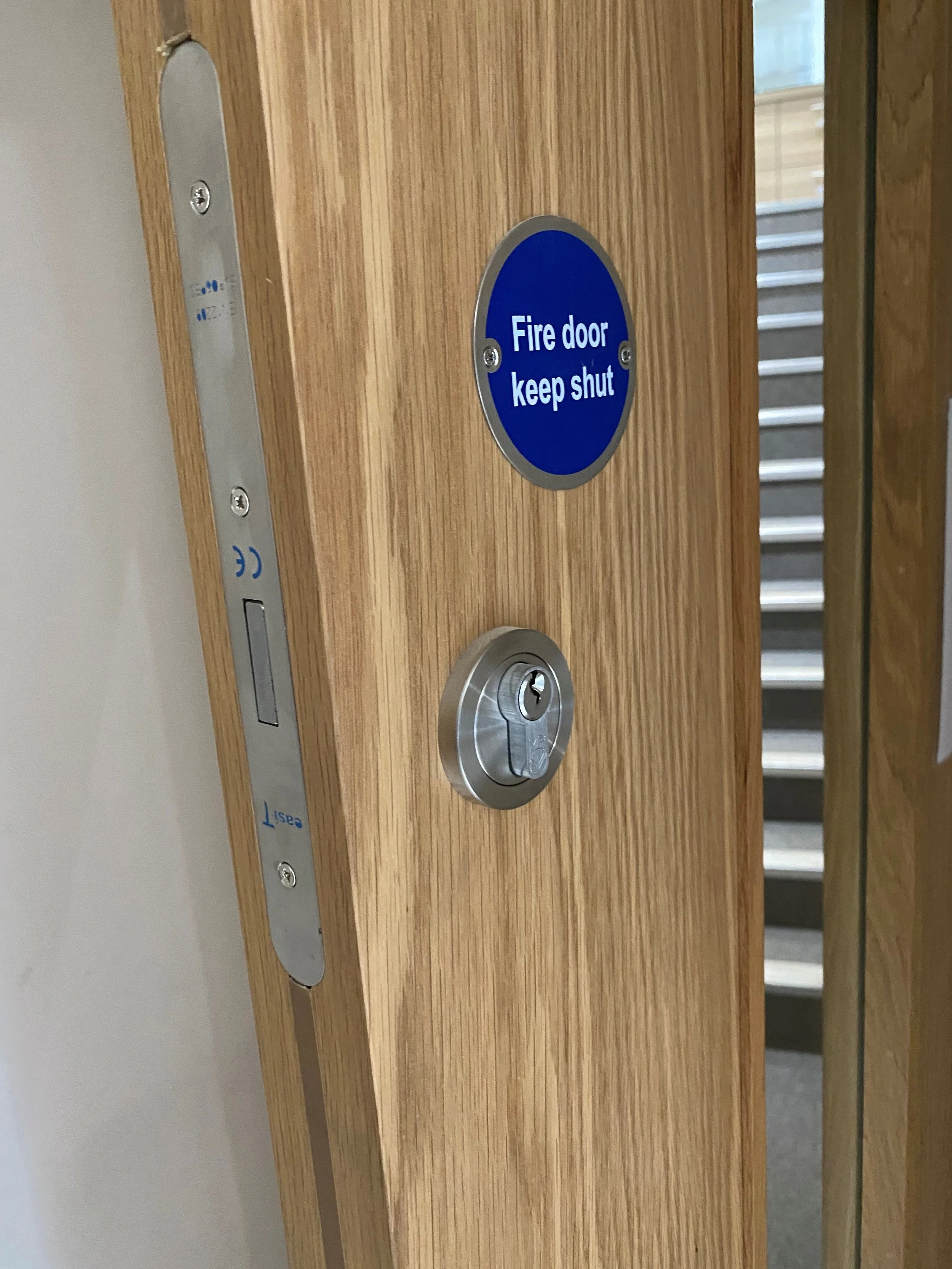 Hospital emergency exit door with warning sign and wall-mounted intercom.