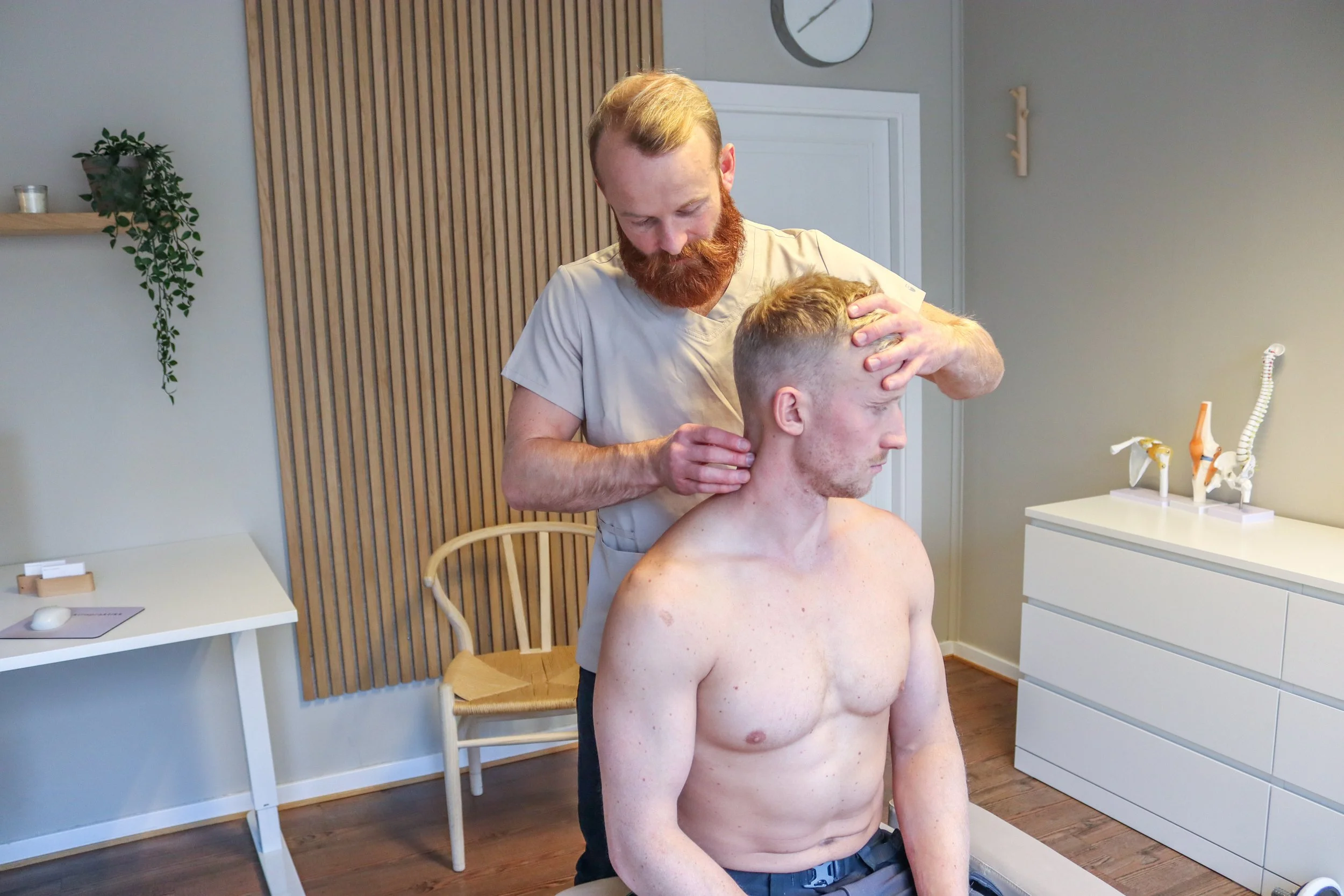 Et bilde som viser James Ellis kiropraktor undersøking en pasient med nakkesmerter