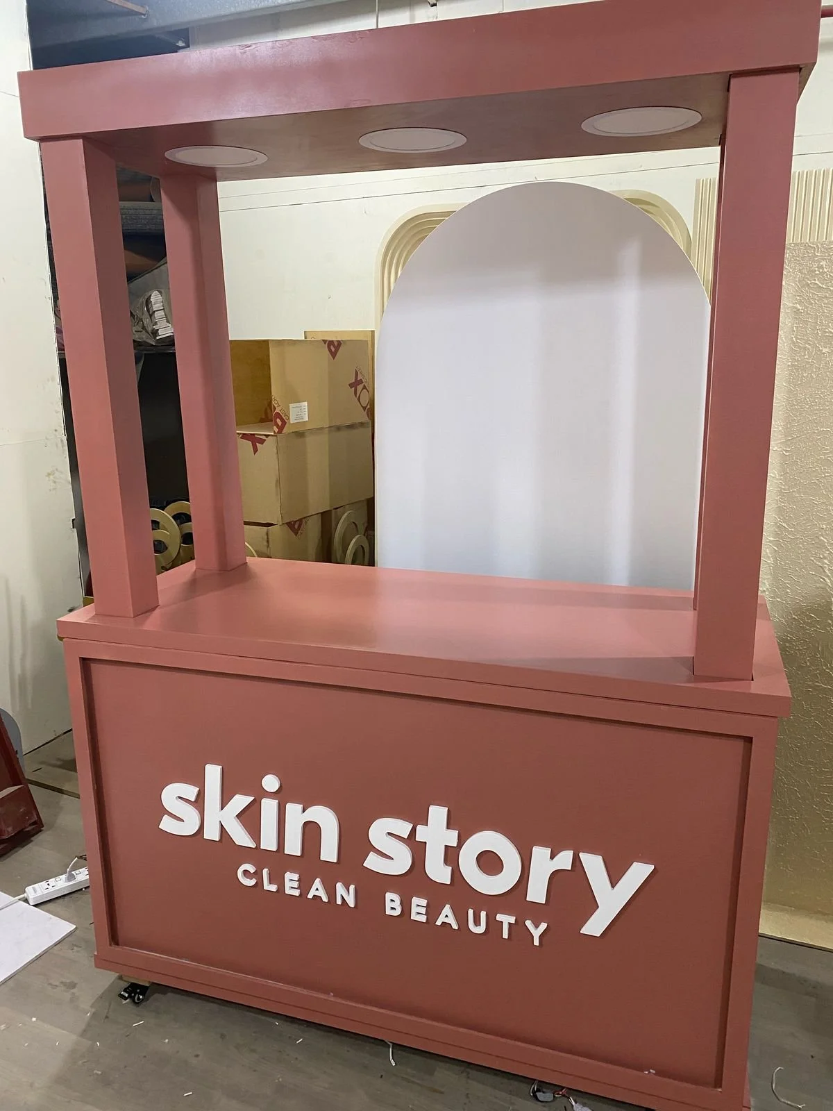 Pink retail display stand with large white sign reading 'skin story CLEAN BEAUTY'