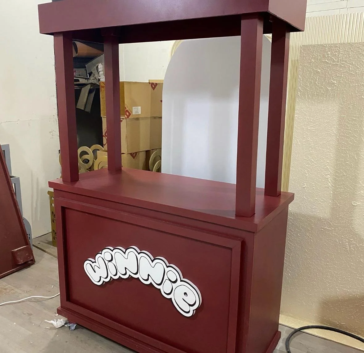 Red wooden stand with a Enormous sign on the front that reads 'WIN WIN' in white letters with a black outline.