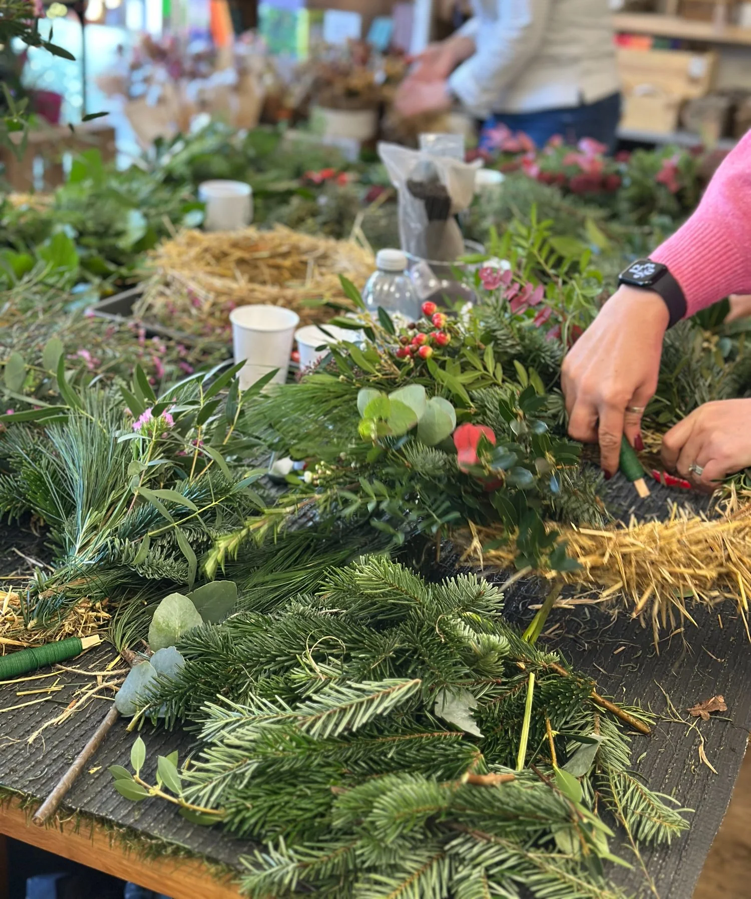 Guests creating natural Christmas wreaths using winter foliage and sustainable straw bases at a Stems at 24 wreath-making workshop in Ruddington.