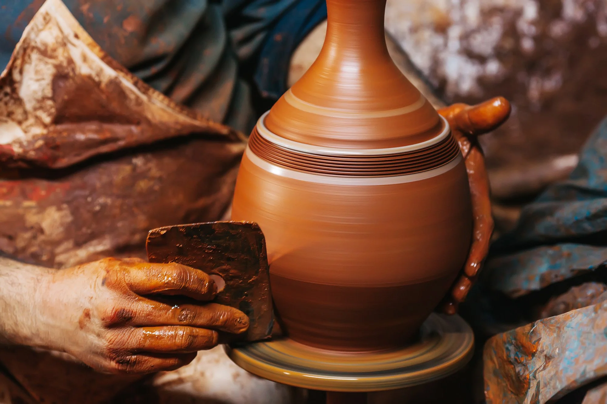 A potter forms a vase on a pottery wheel.