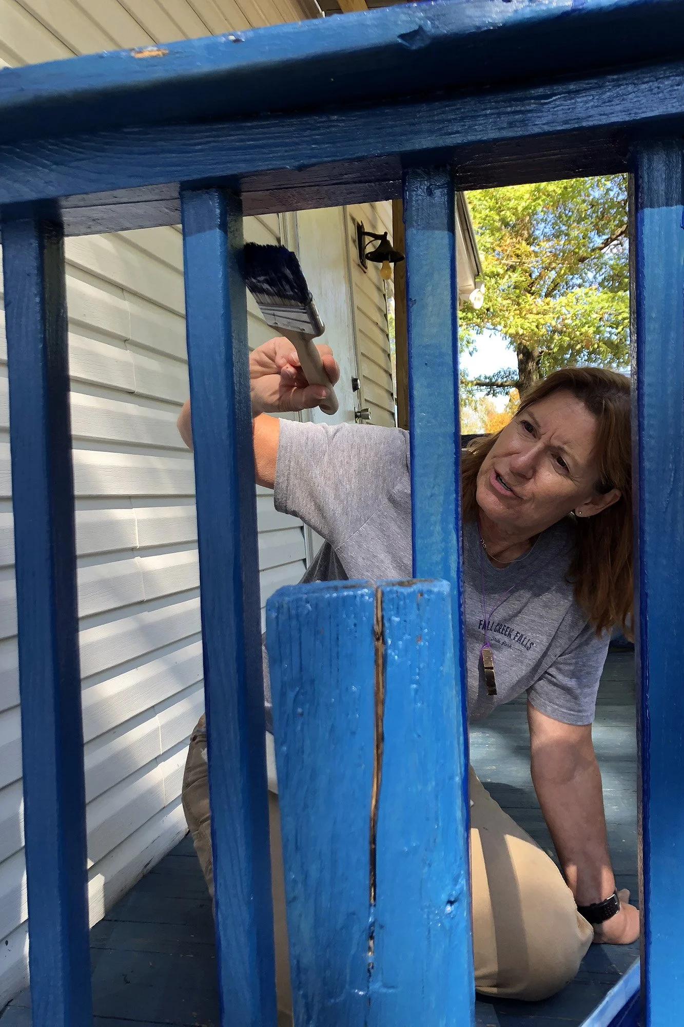 A volunteer paints decking pickets.