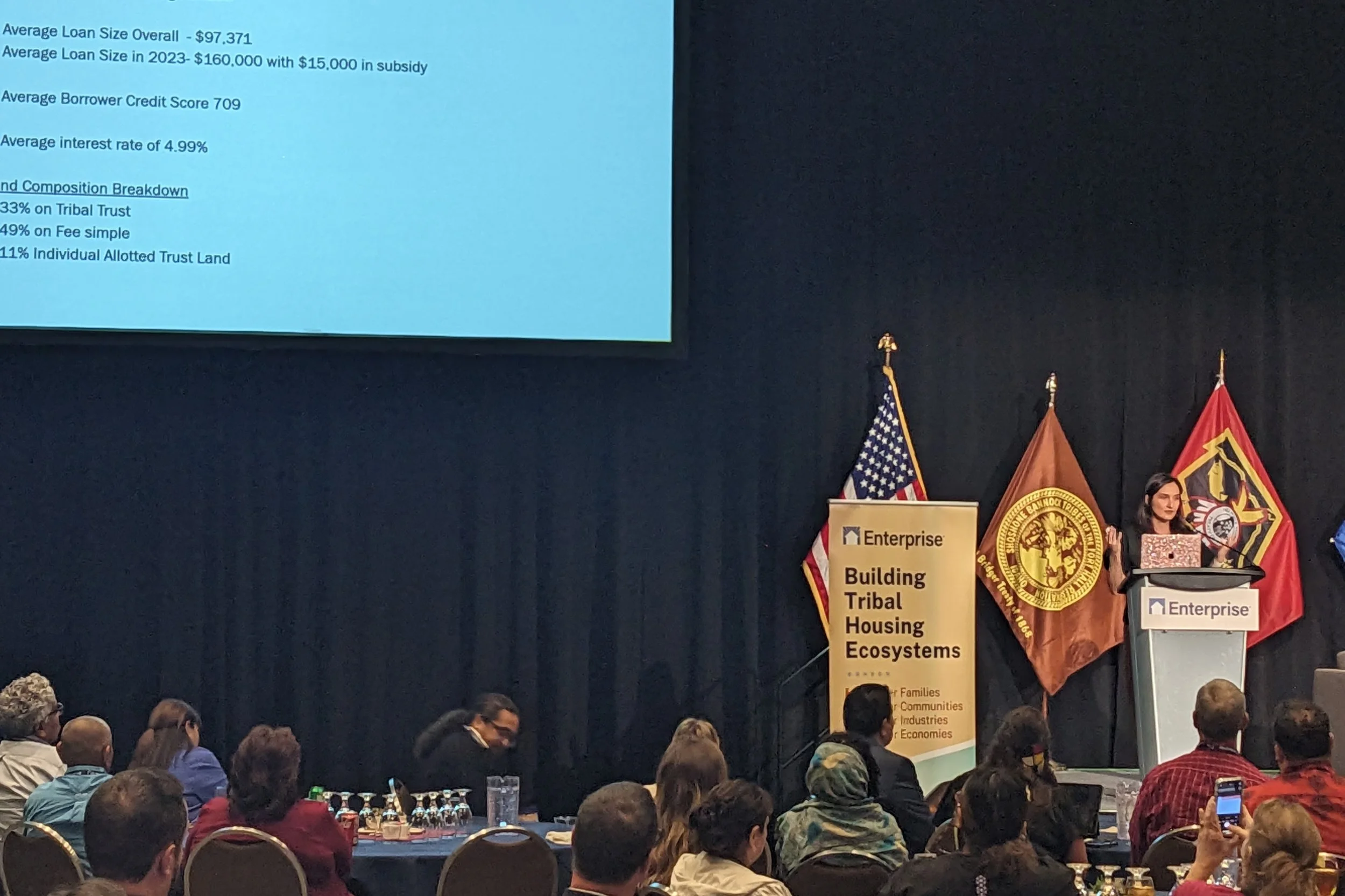 Lakota Vogel speaking on a stage to attendees.