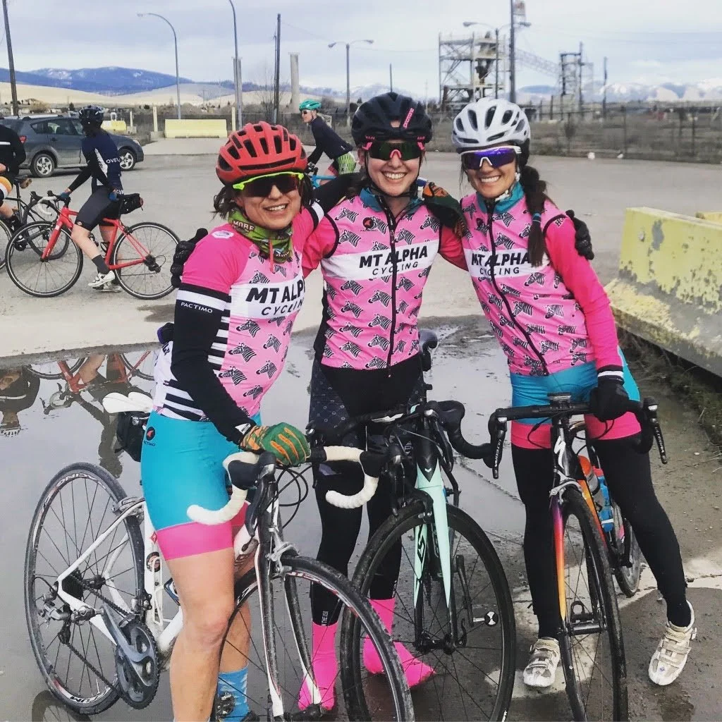 Three female riders on bikes smiling at the camera.