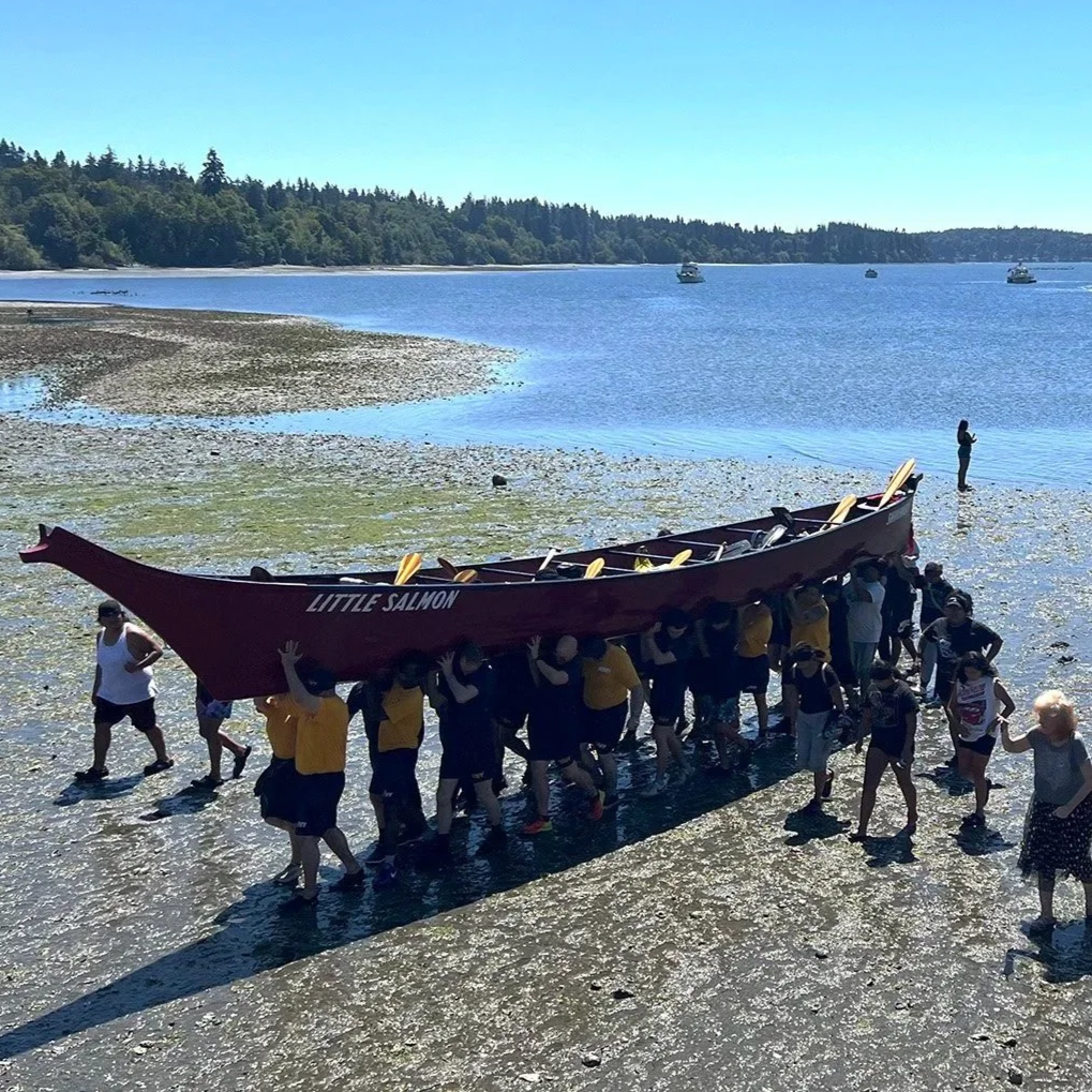 Tribal members carrying a canoe out of the water near Little Boston, Washington