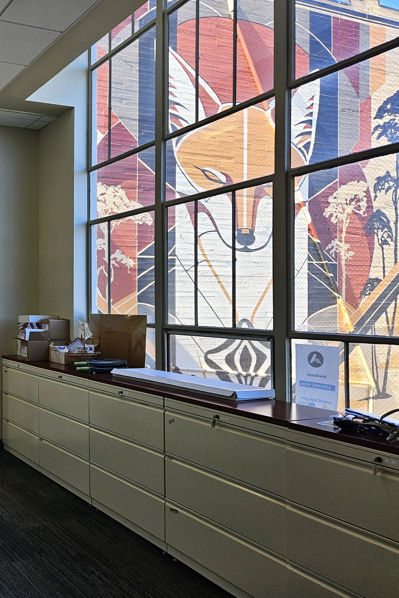 Inside UWMC's headquarters looking through a window onto an outdoor wall mural of a fox and other geometrical shapes.