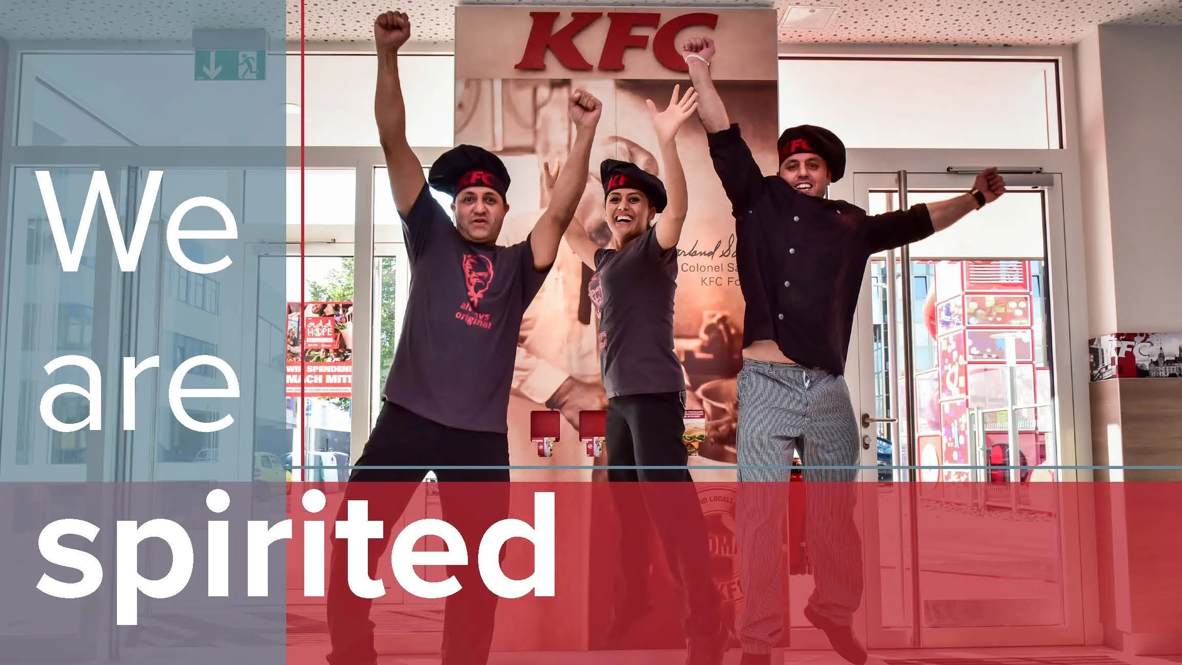 Three people dressed as KFC employees cheering with their arms raised inside a KFC restaurant.
