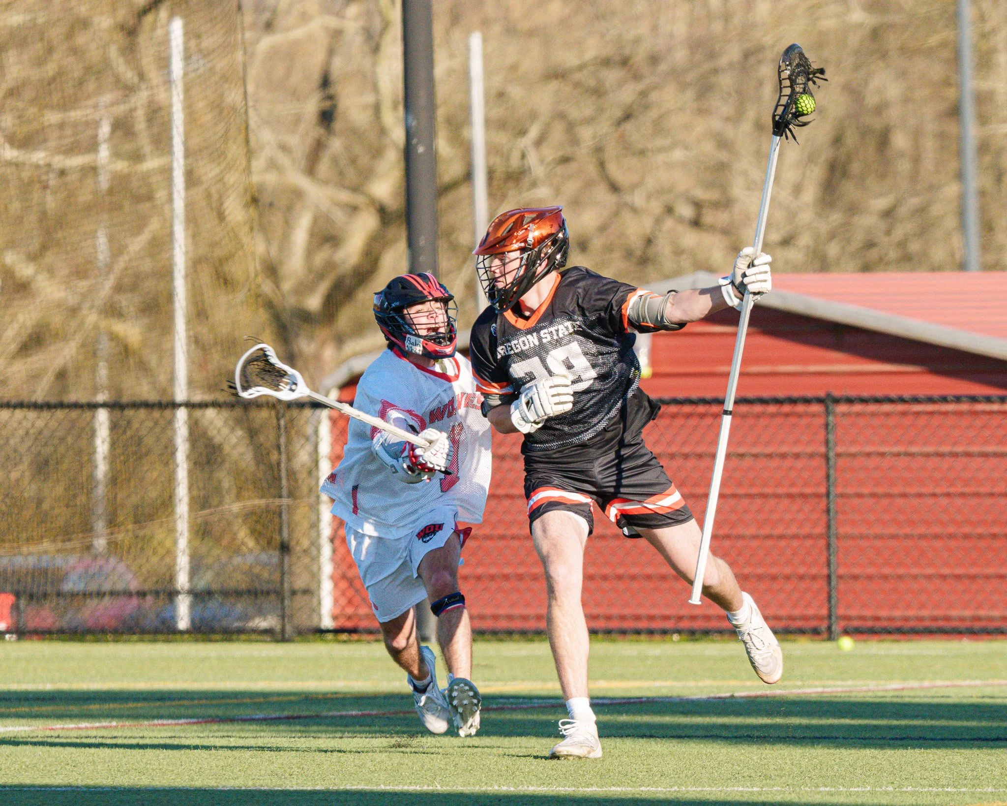 I love it when the roles are reversed!  Now the defender has his stick in a defensive position away from the opposing player (who is about to land a check) as he attempts to make an escape.  Both of the players have great expressions on their faces t