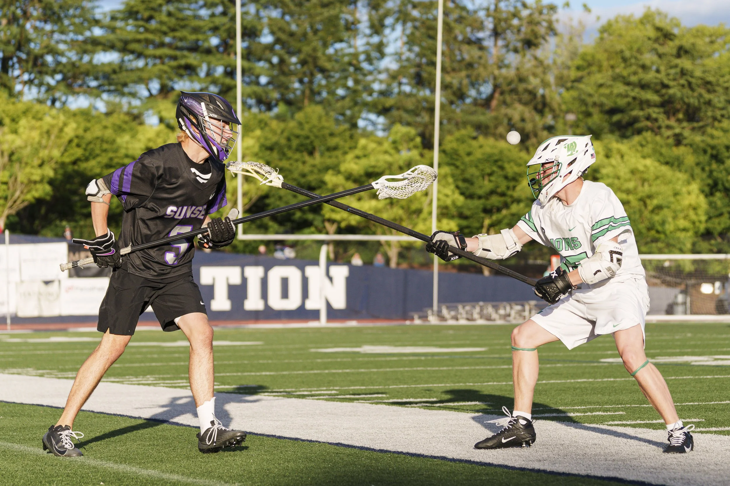Two high school lacrosse players fight for a loose ball.