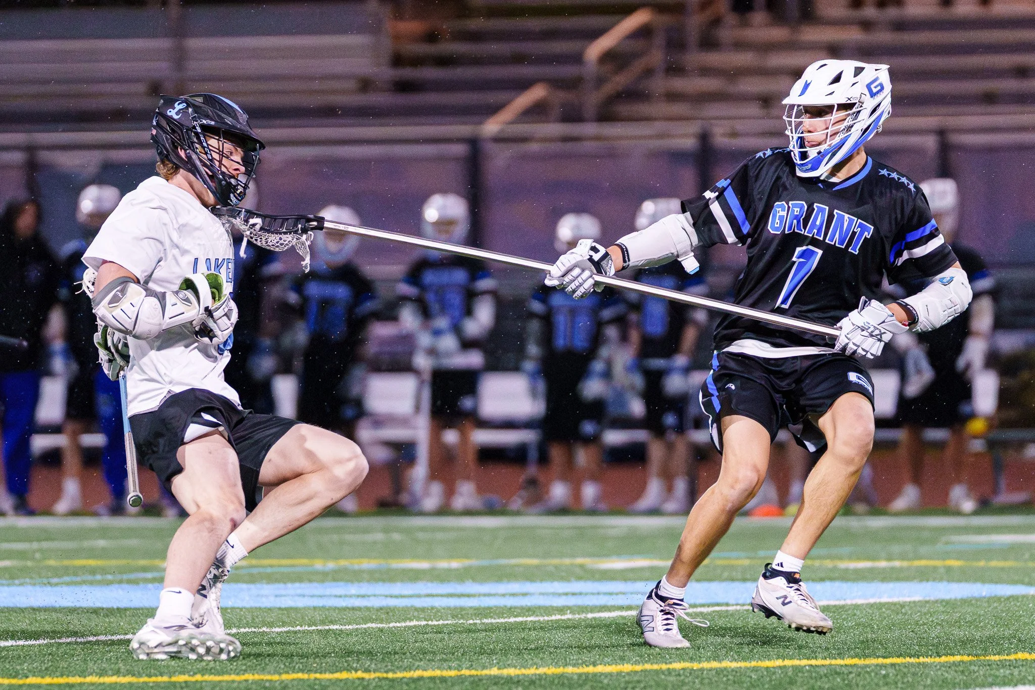 Two high school lacrosse players run toward a ground ball.