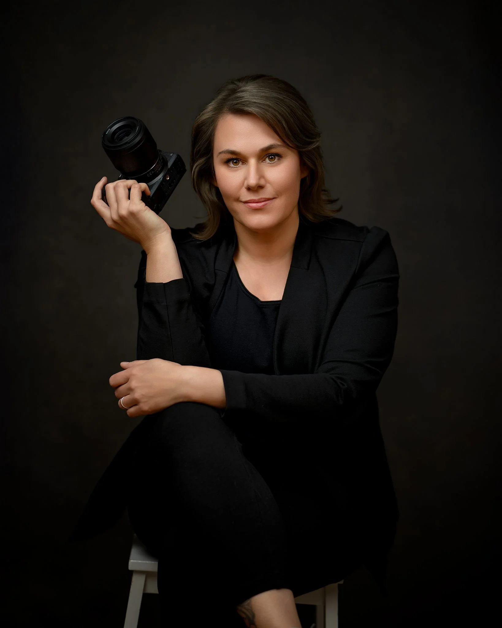 Portrait Photographer dressed in black holding a Nikon camera.