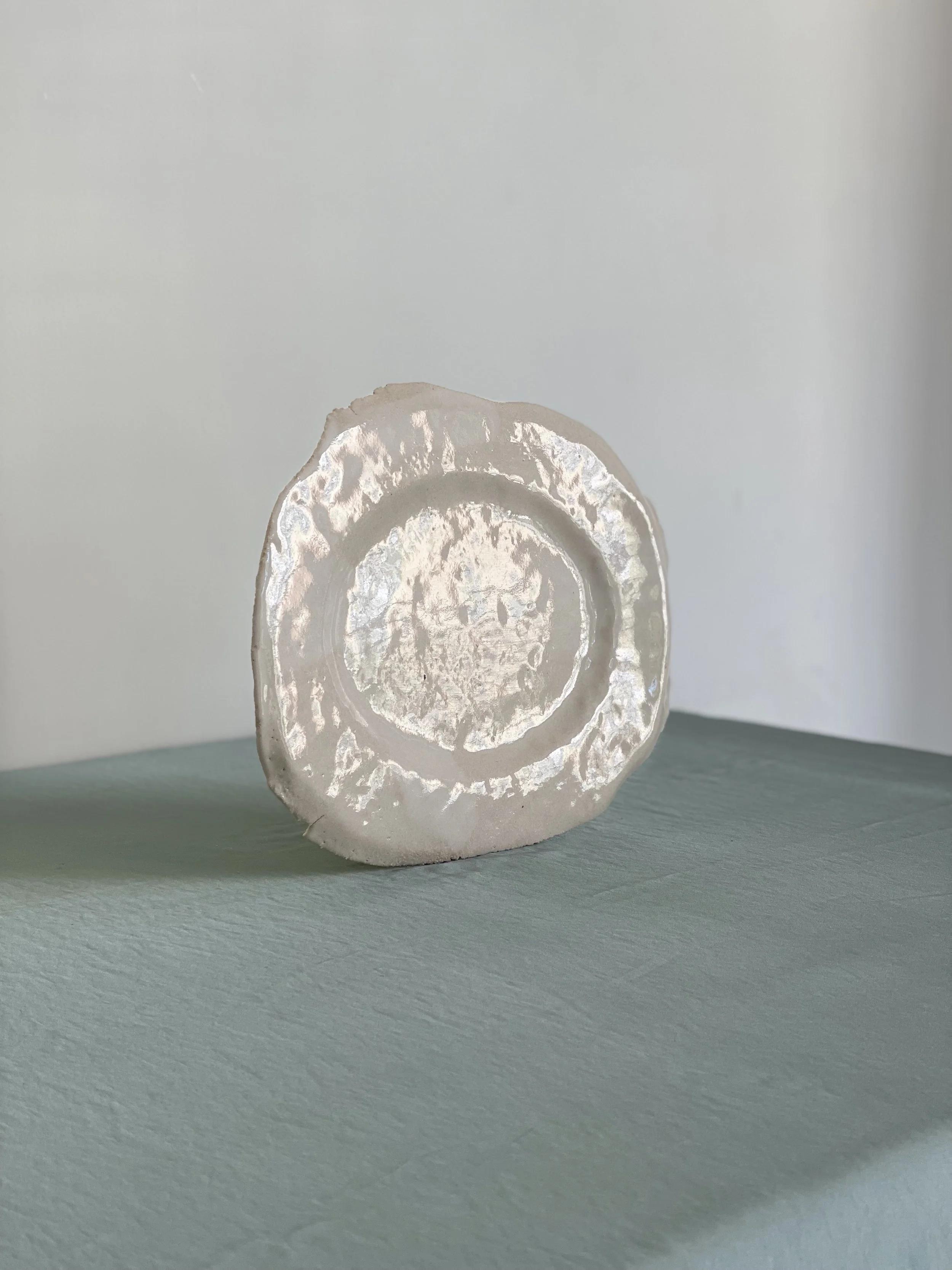 Corte transversal de una piedra preciosa, probablemente ónix, con patrones circulares y detalles en tonos claros y oscuros, colocada sobre una superficie verde.