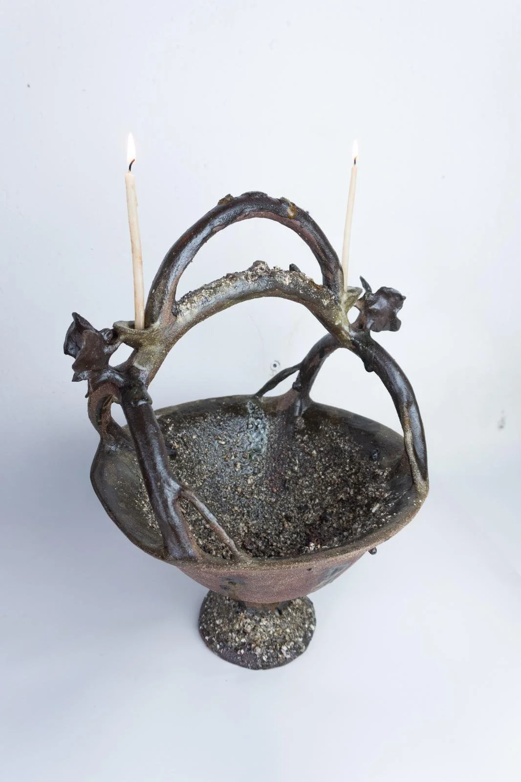 Cáliz de cerámica con decoración en forma de ramas y estrellas, con dos cerillos encendidos.