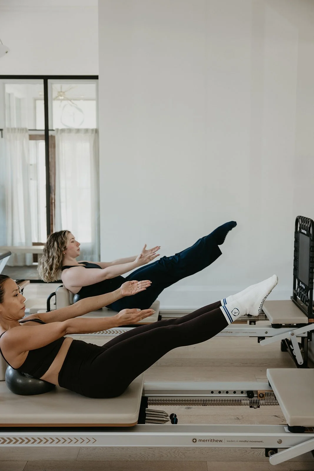 two women jumping on the reformer machine with the assistance of a cardio trampoline