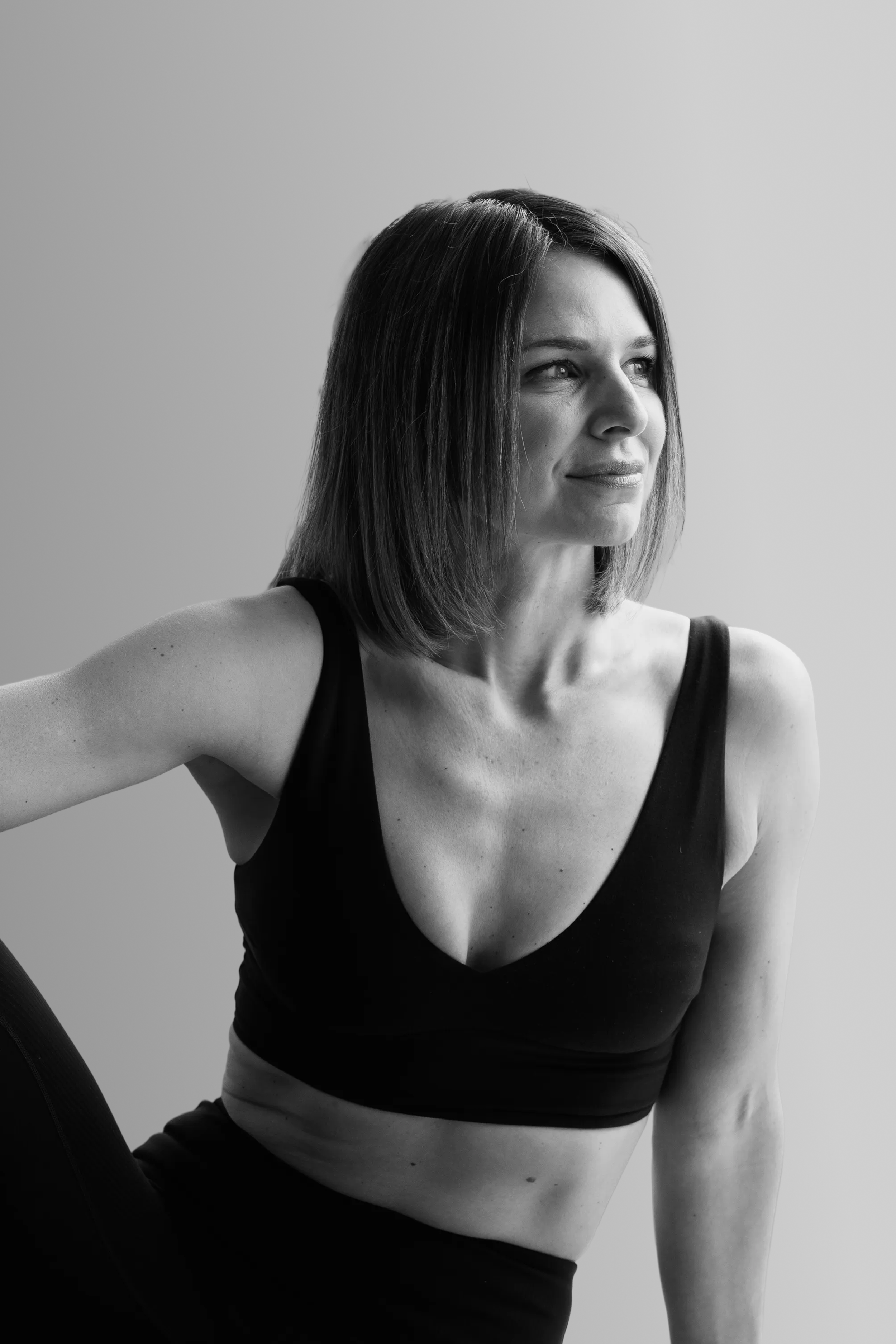 Black and white portrait of a smiling woman with short straight hair, wearing a sleeveless top.